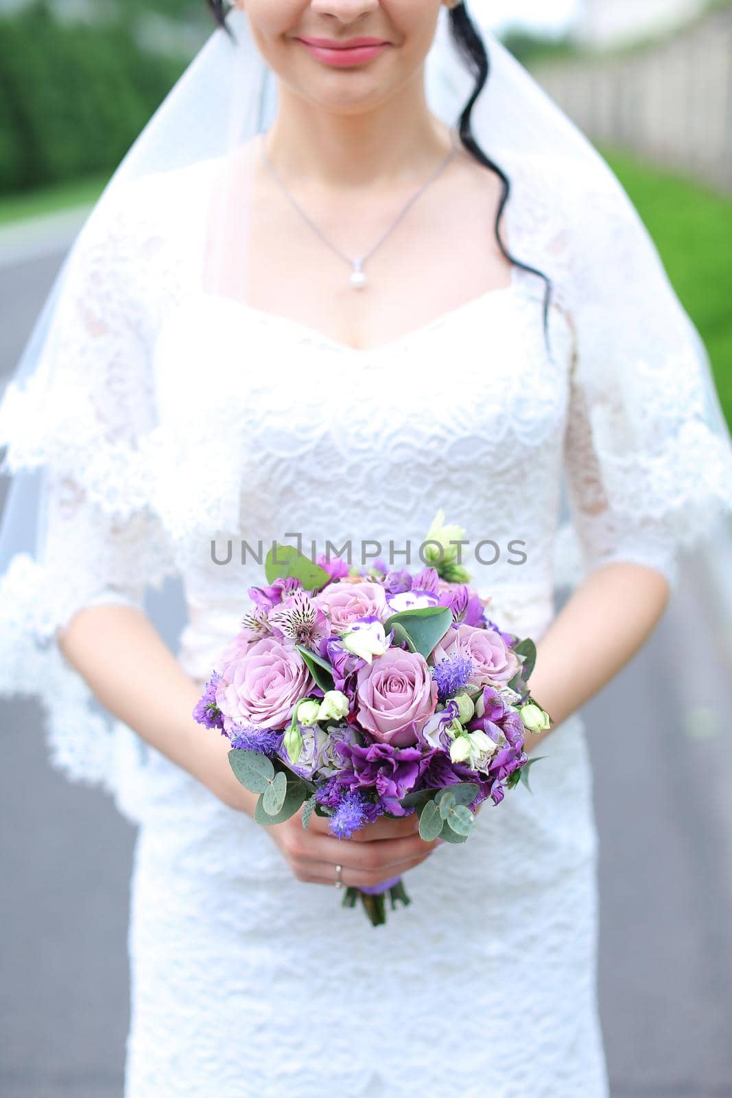 Bride keeping violet bouquet of flowers. Concept of wedding and floristic art.