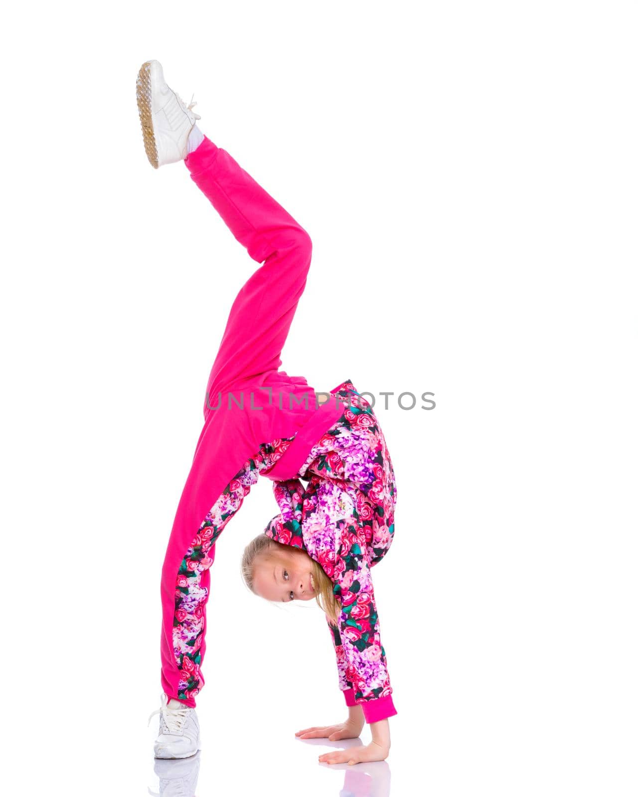 A girl gymnast performs an acrobatic element on the floor. The concept of childhood, sport, healthy lifestyle. Isolated on white background.