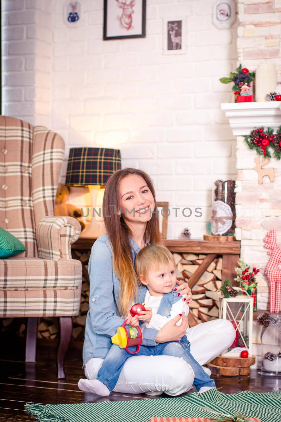 Young mother sitting with little daughter in decorated room for Christmas. by sisterspro