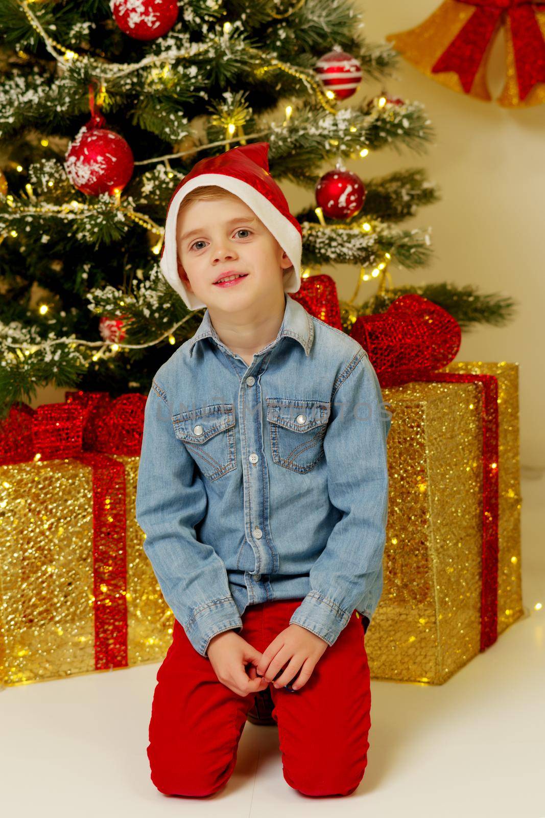 A cute little boy near a Christmas tree with a gift. Concept of family holidays, Happy childhood.