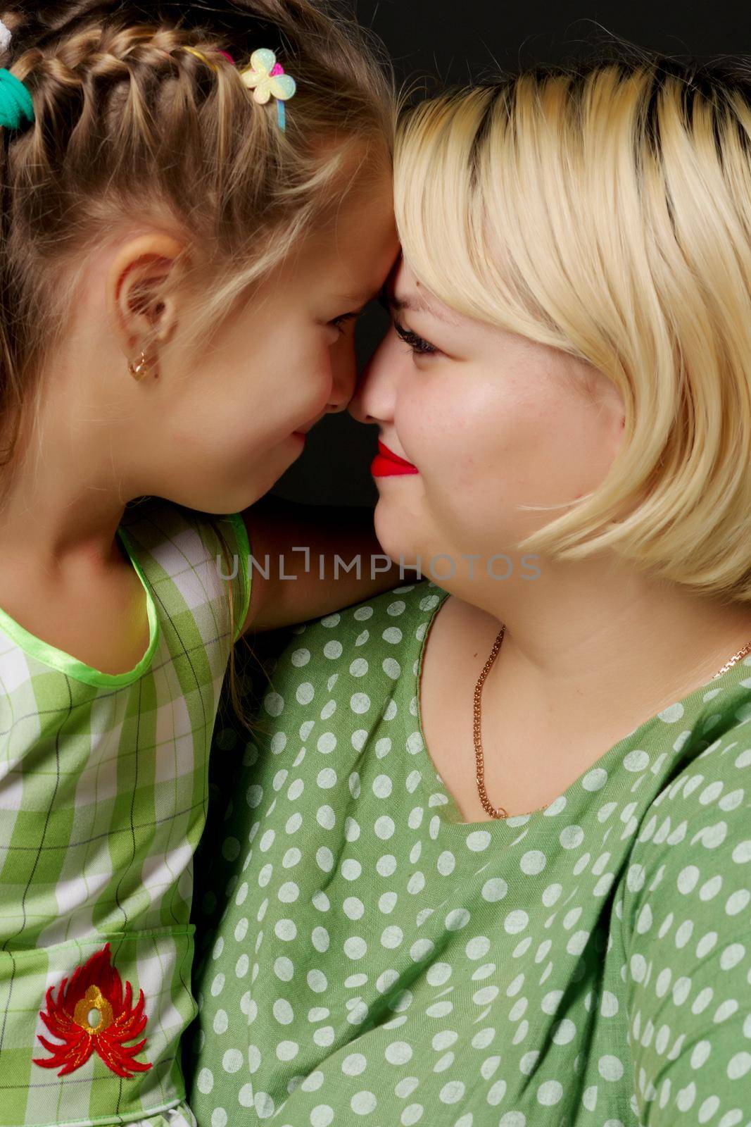 Mom and daughter are hugging on a black background. by kolesnikov_studio