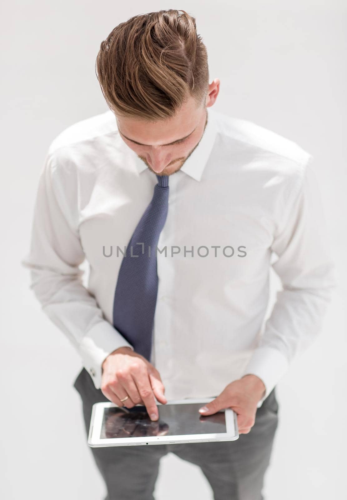 Examining new gadget. A confident man in a shirt and tie works on a digital tablet