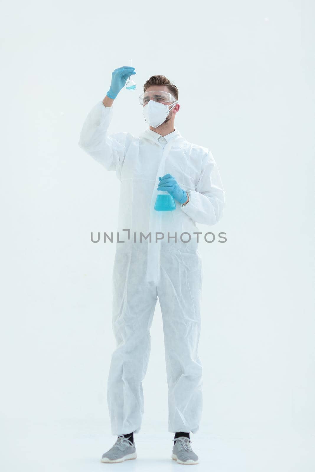 in full growth.a scientist in a protective suit looking at a bottle of liquid