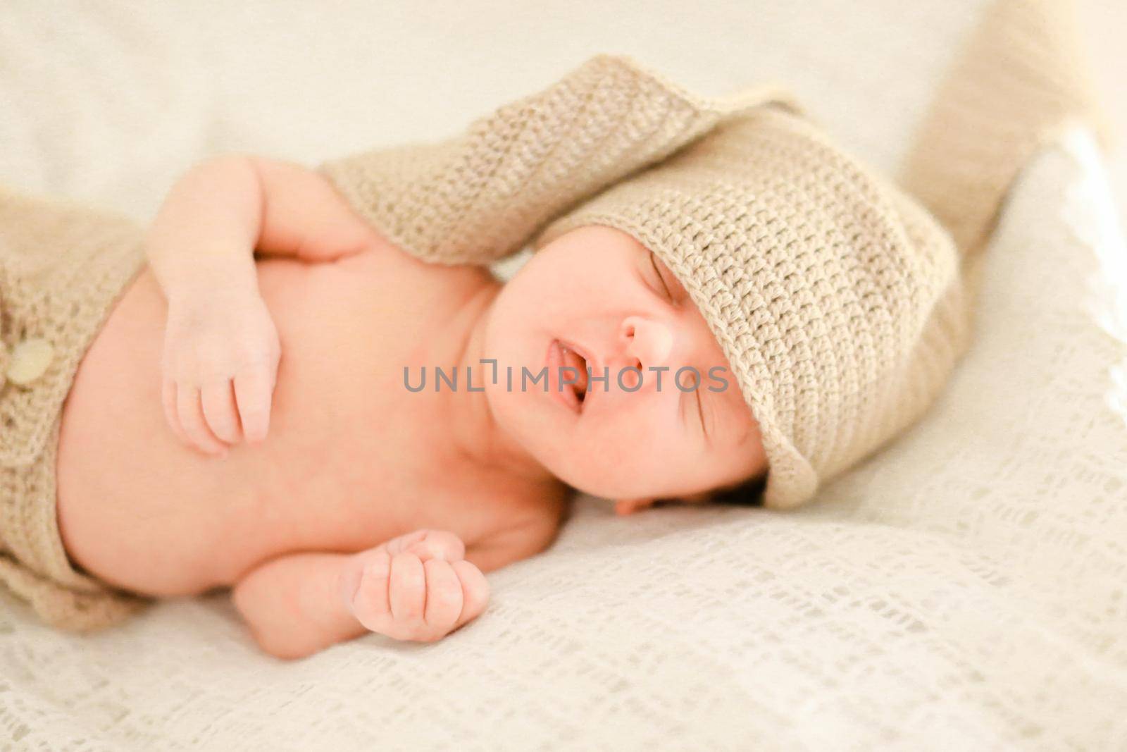 Nice newborn baby sleeping and wearing crocheted clothes, white background. Concept of babies and new life.