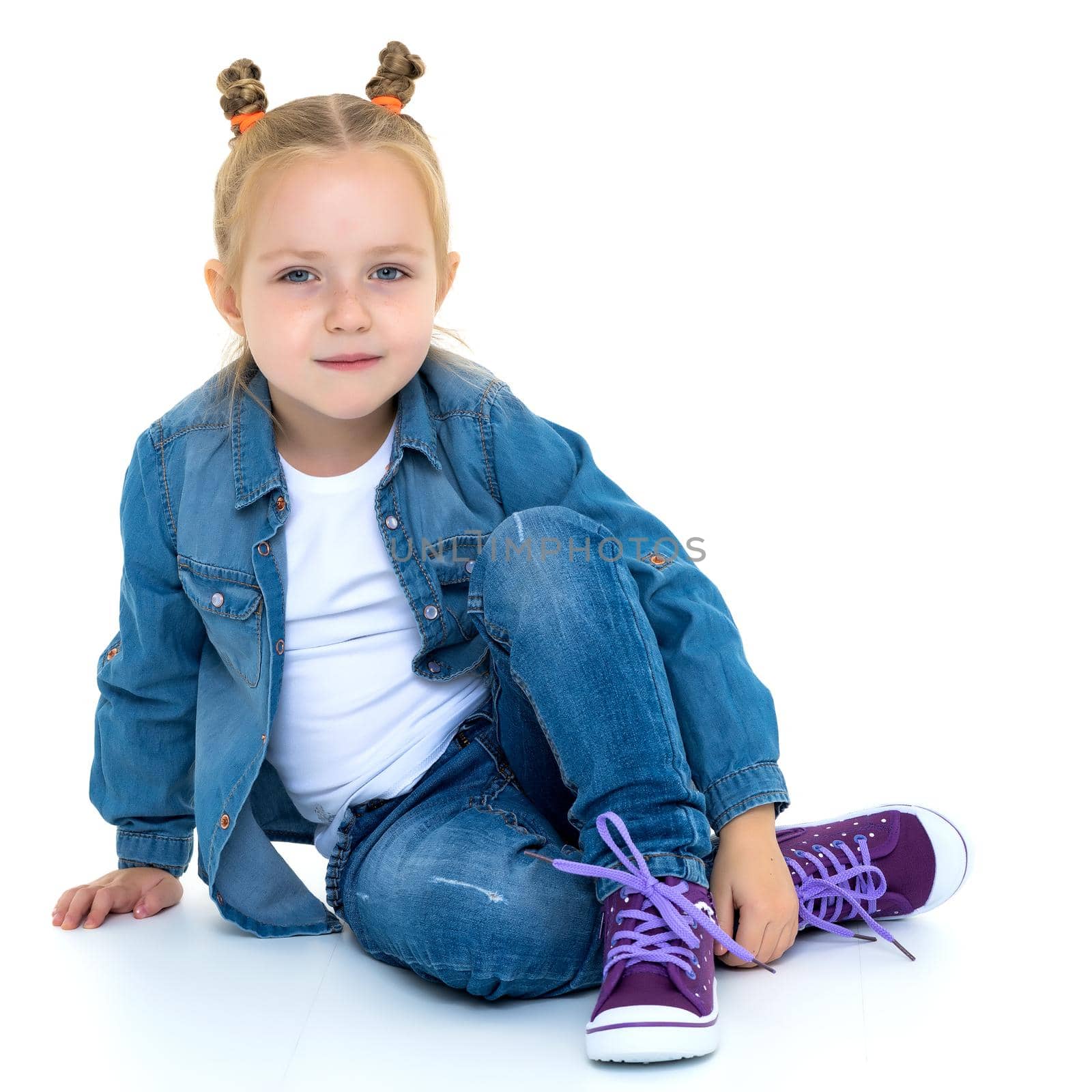 Little girl is sitting on the floor. The concept of a happy childhood. Isolated on white background.