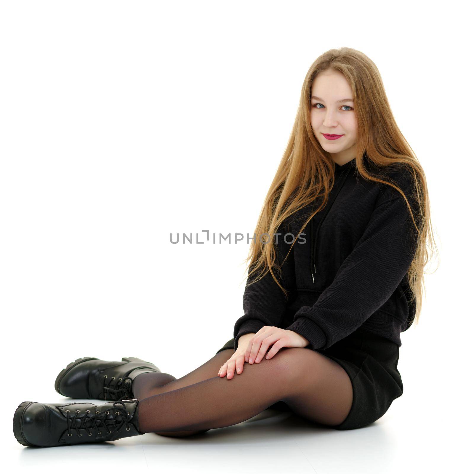 A beautiful teen girl sits on the floor on a white background. The concept of education and schoo. Isolated.