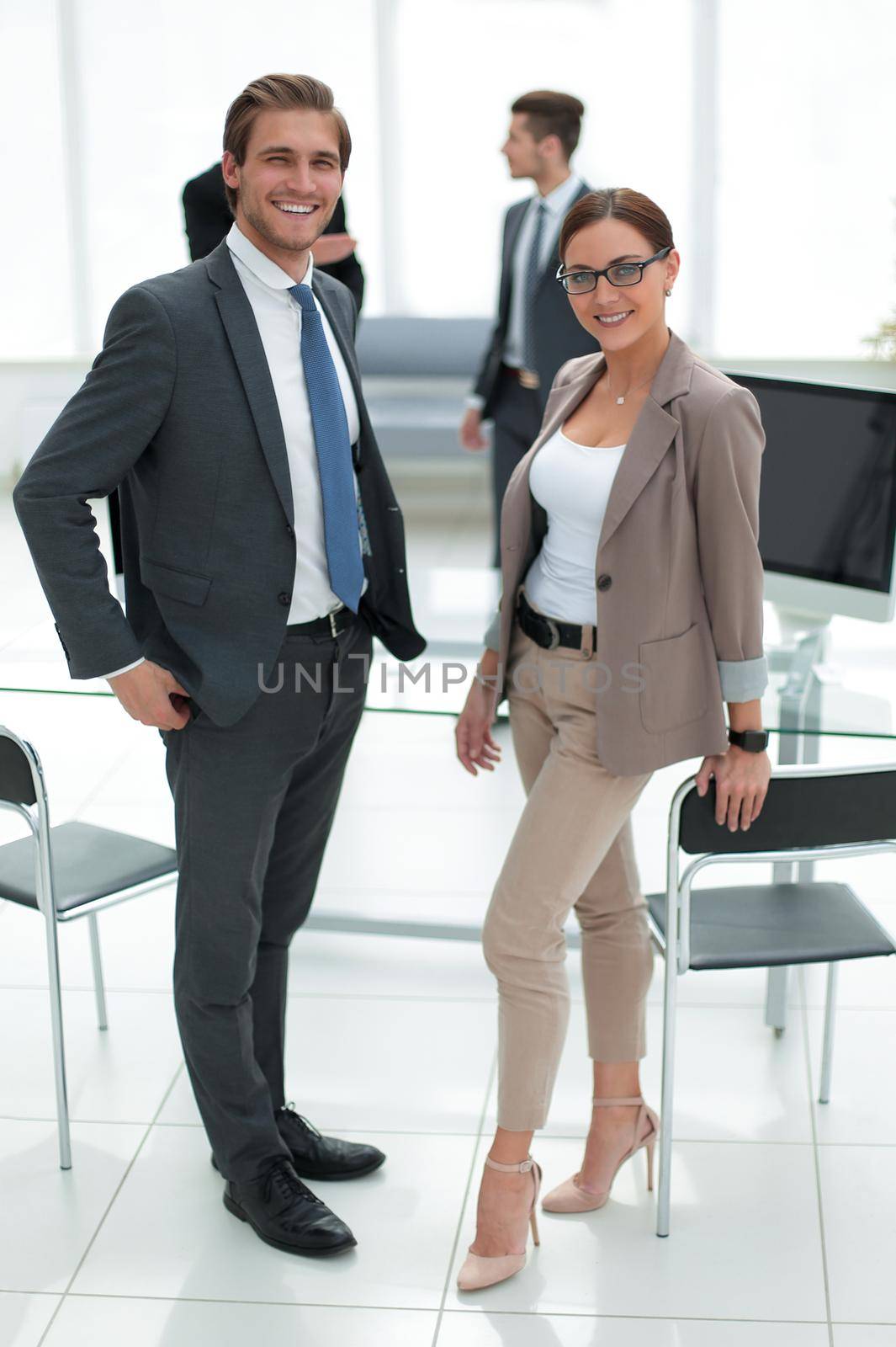 businessman and business woman standing in office talking with the receptionist. by asdf