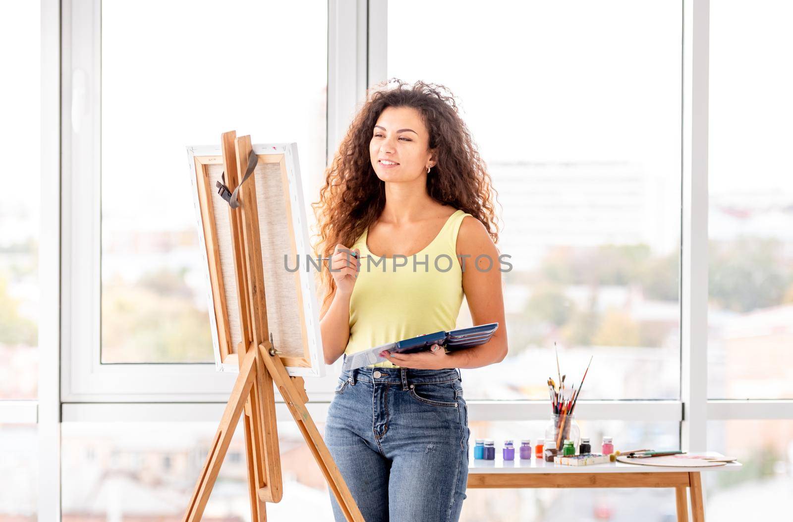 Lovely painter near easel in atelier