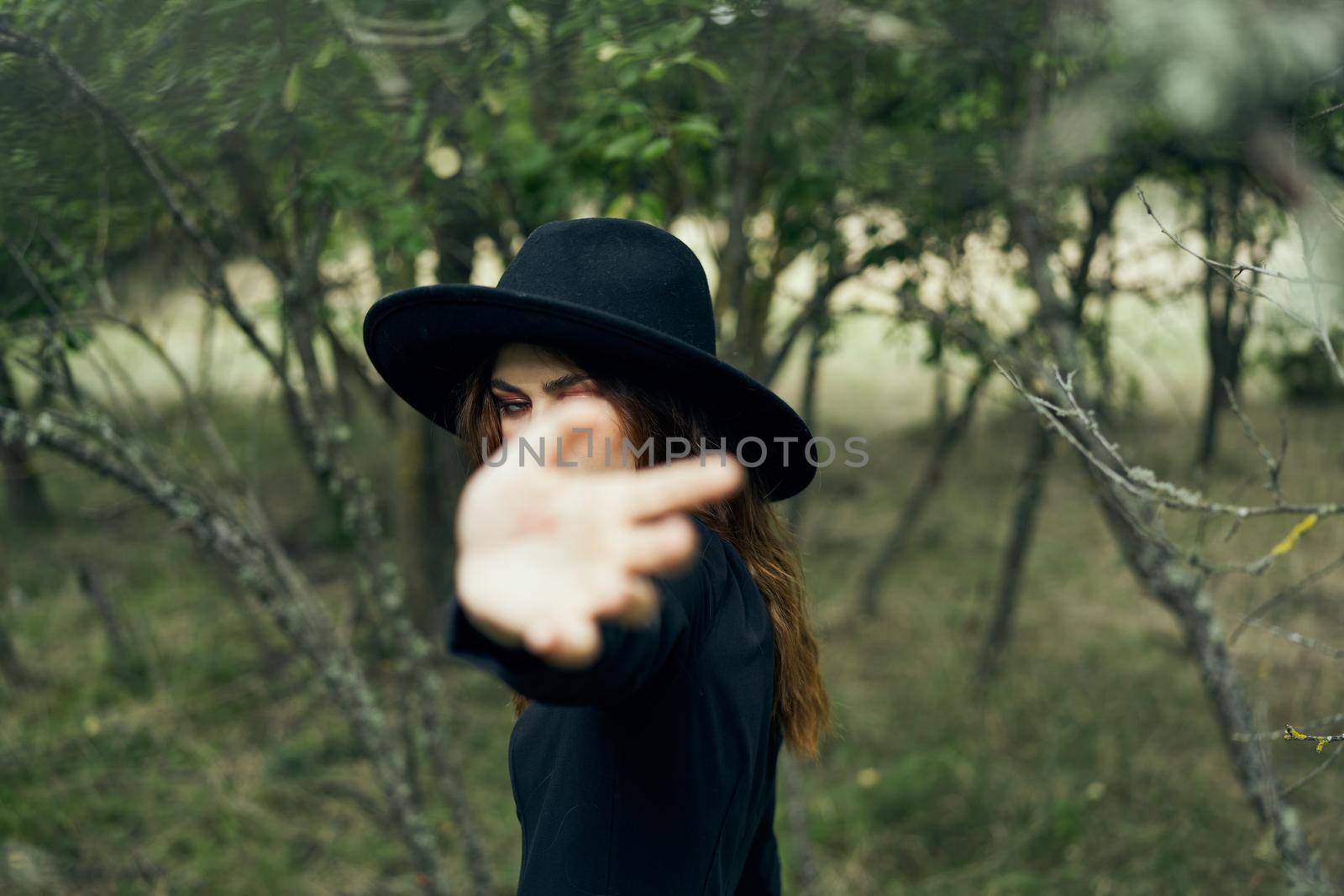woman in a black hat gesturing with her hands witch magic fantasy. High quality photo