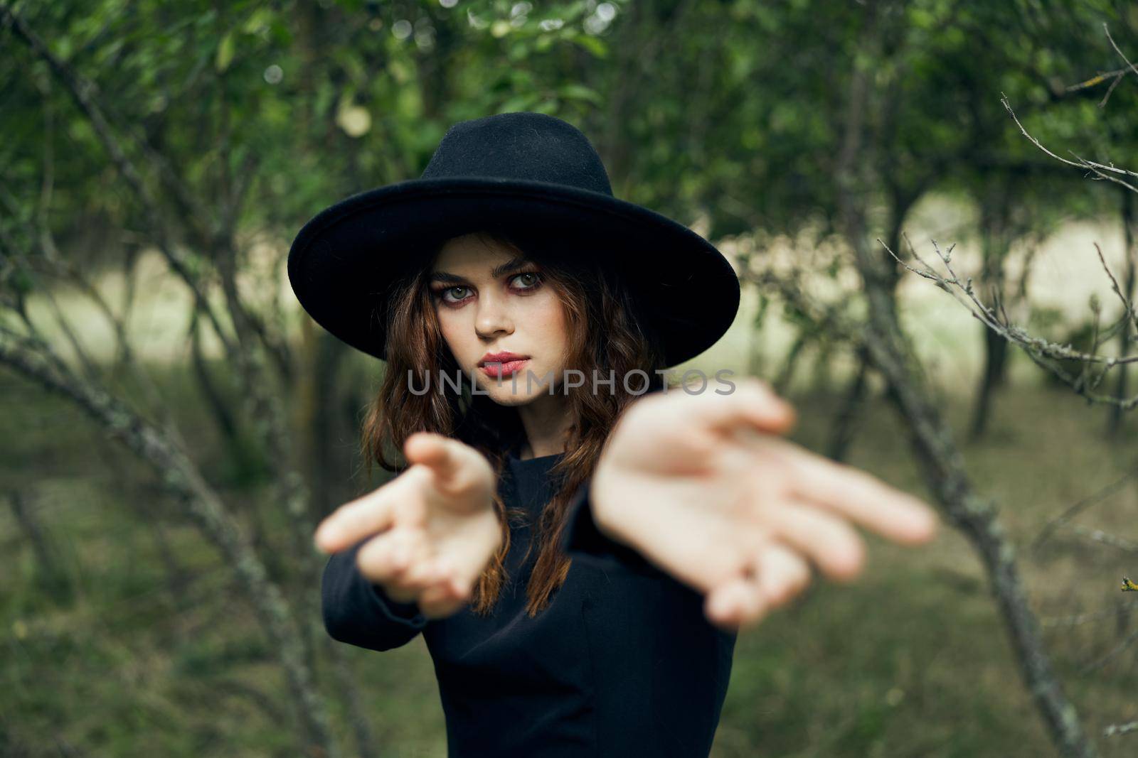 woman in black witch costume in forest nature posing. High quality photo