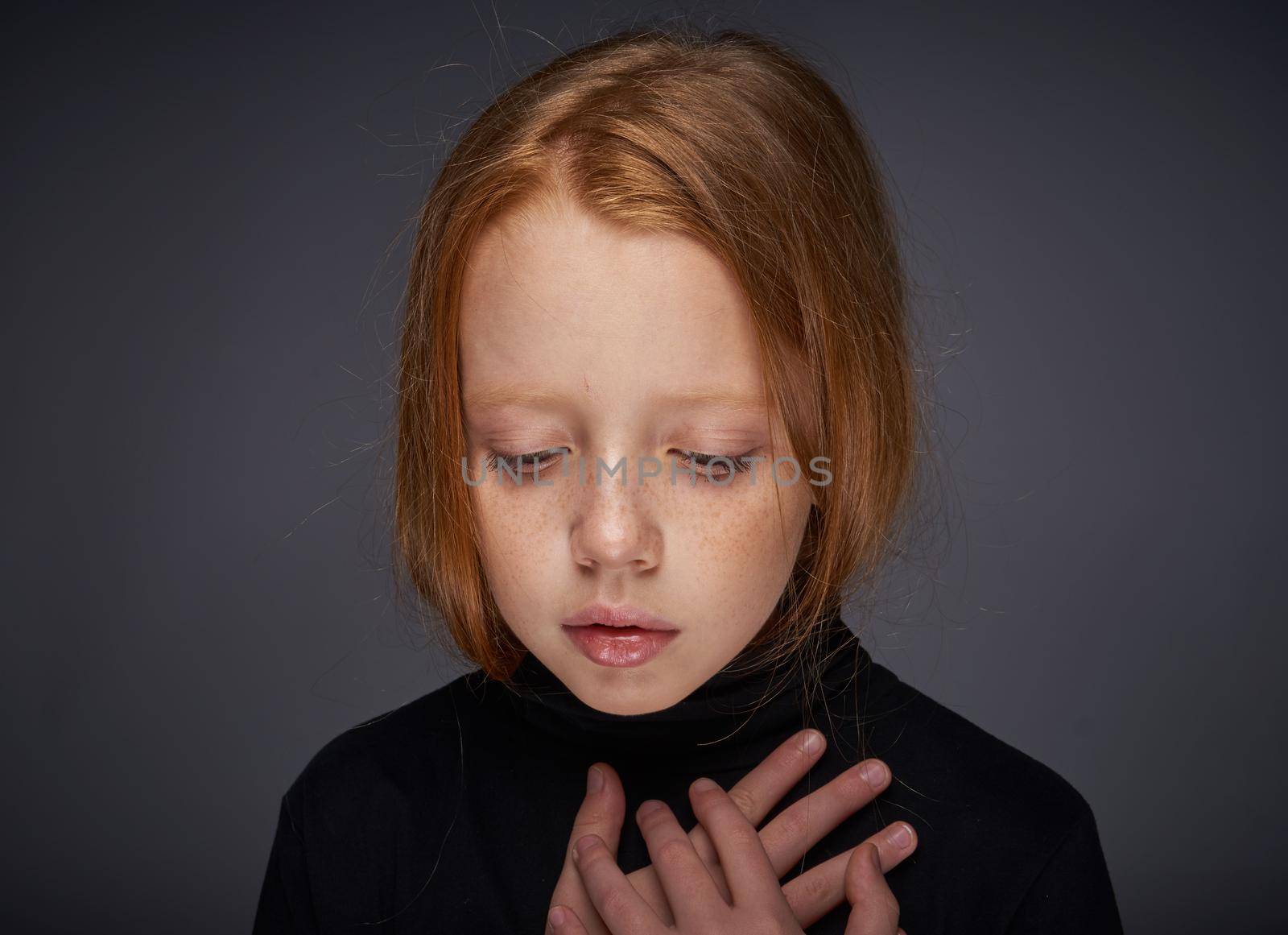 red-haired girl with freckles on her face in a black sweater posing. High quality photo