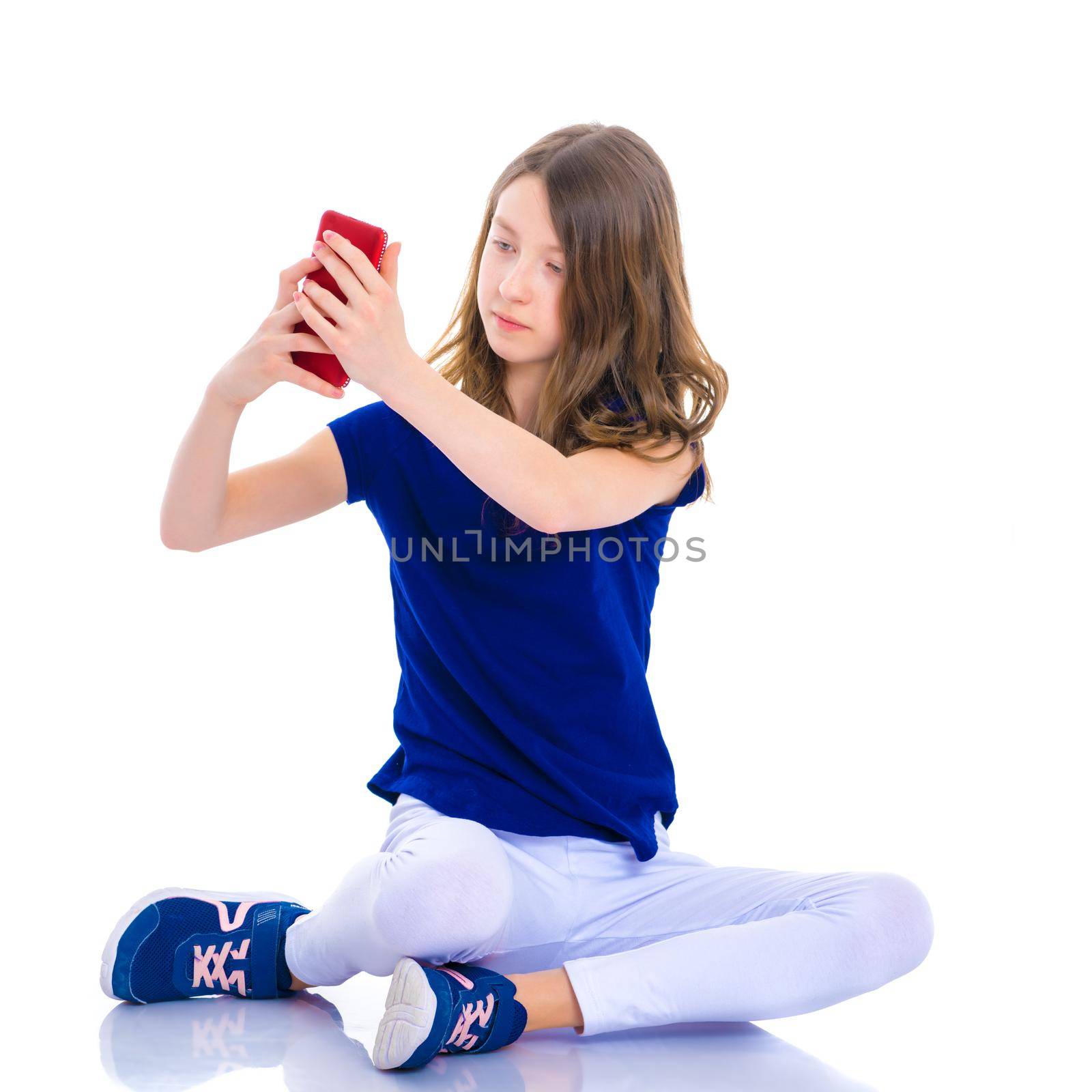 Happy smiling little girl making self-portrait on smartphone. The concept of people and technology. Isolated on white background.