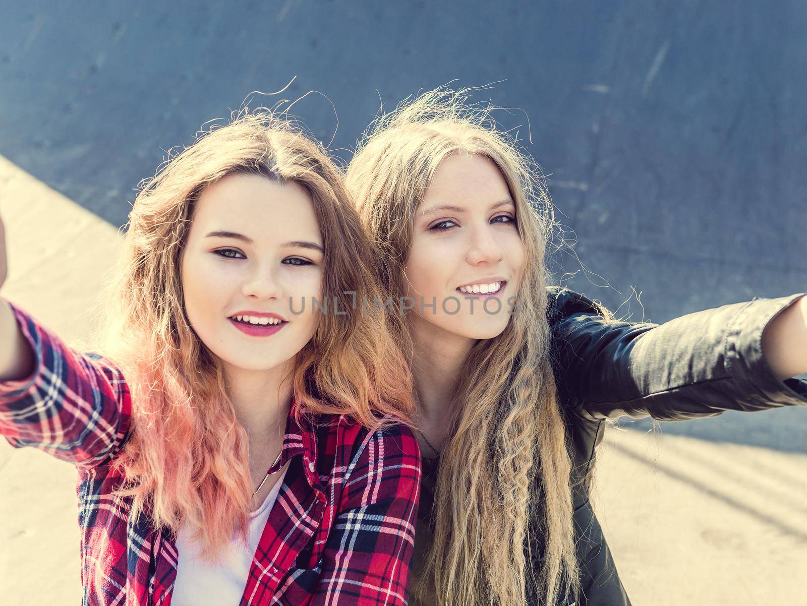 Happy girl friends taking a selfie on a summer day. Two teen girl having fun while making selfie on smartphone