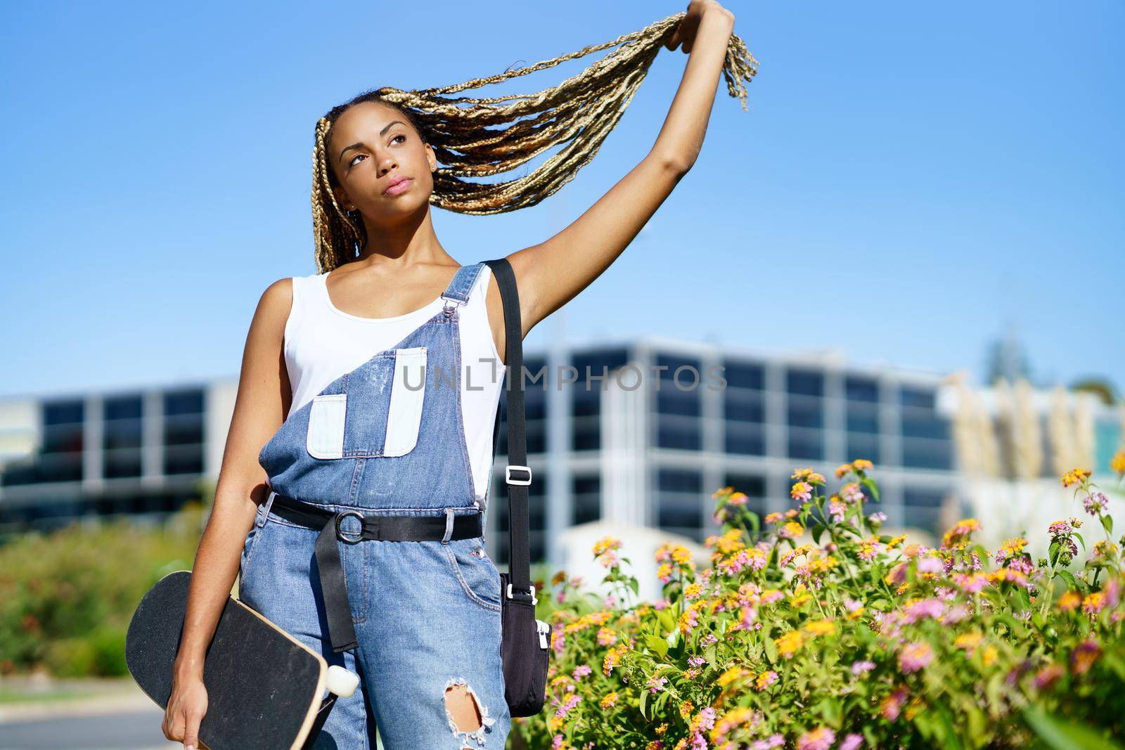 Beautiful young black woman holding her coloured braids. Typical African hairstyle.