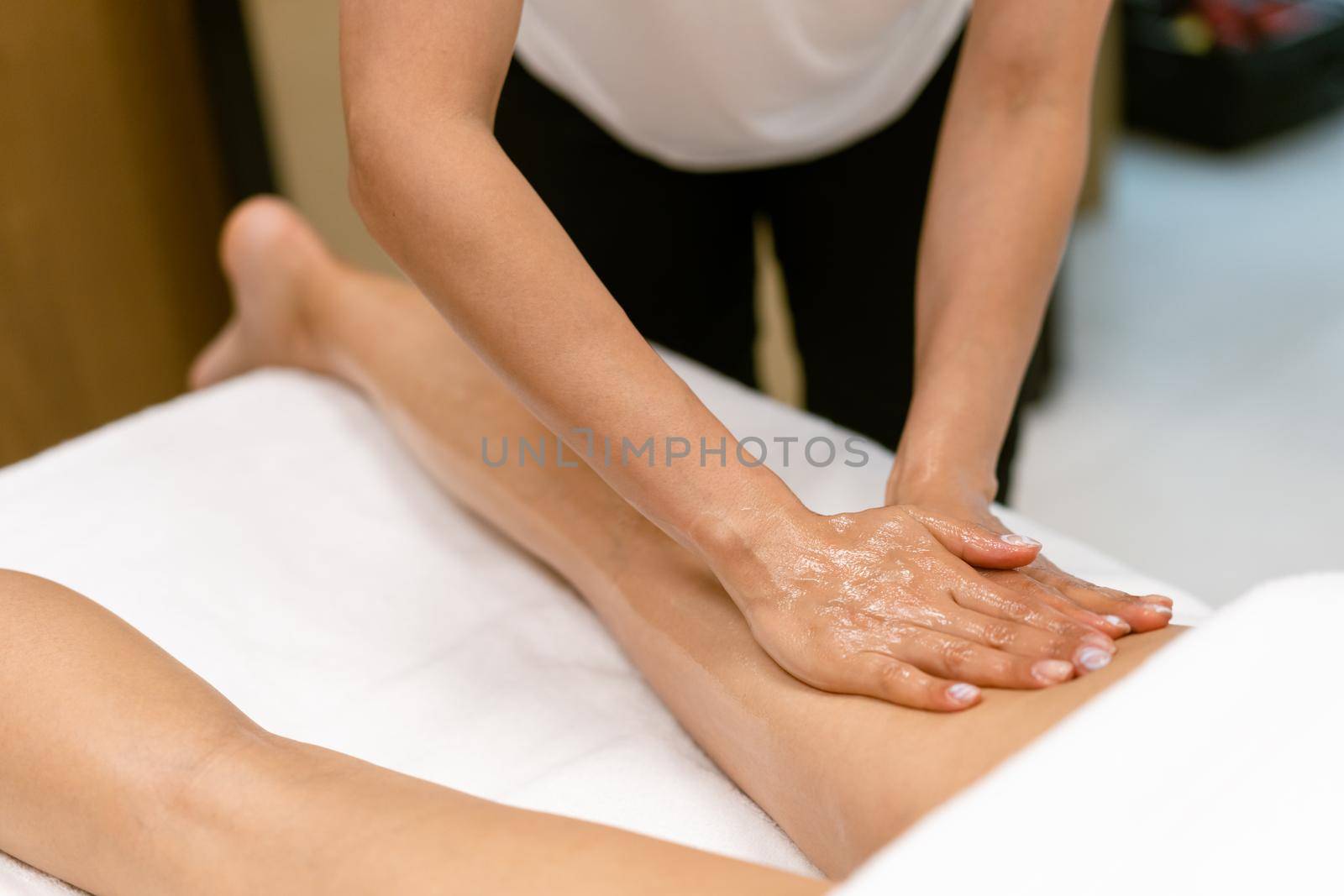 Beauty salon professional pouring oil from a massage candle on the back of his patient. by javiindy