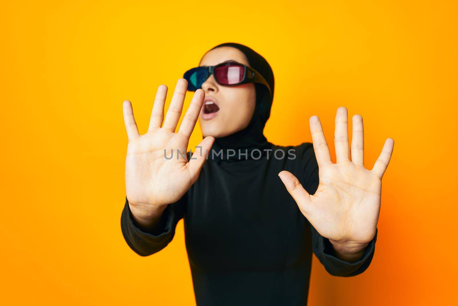 cheerful woman in black hijab popcorn 3D glasses cinema yellow background. High quality photo