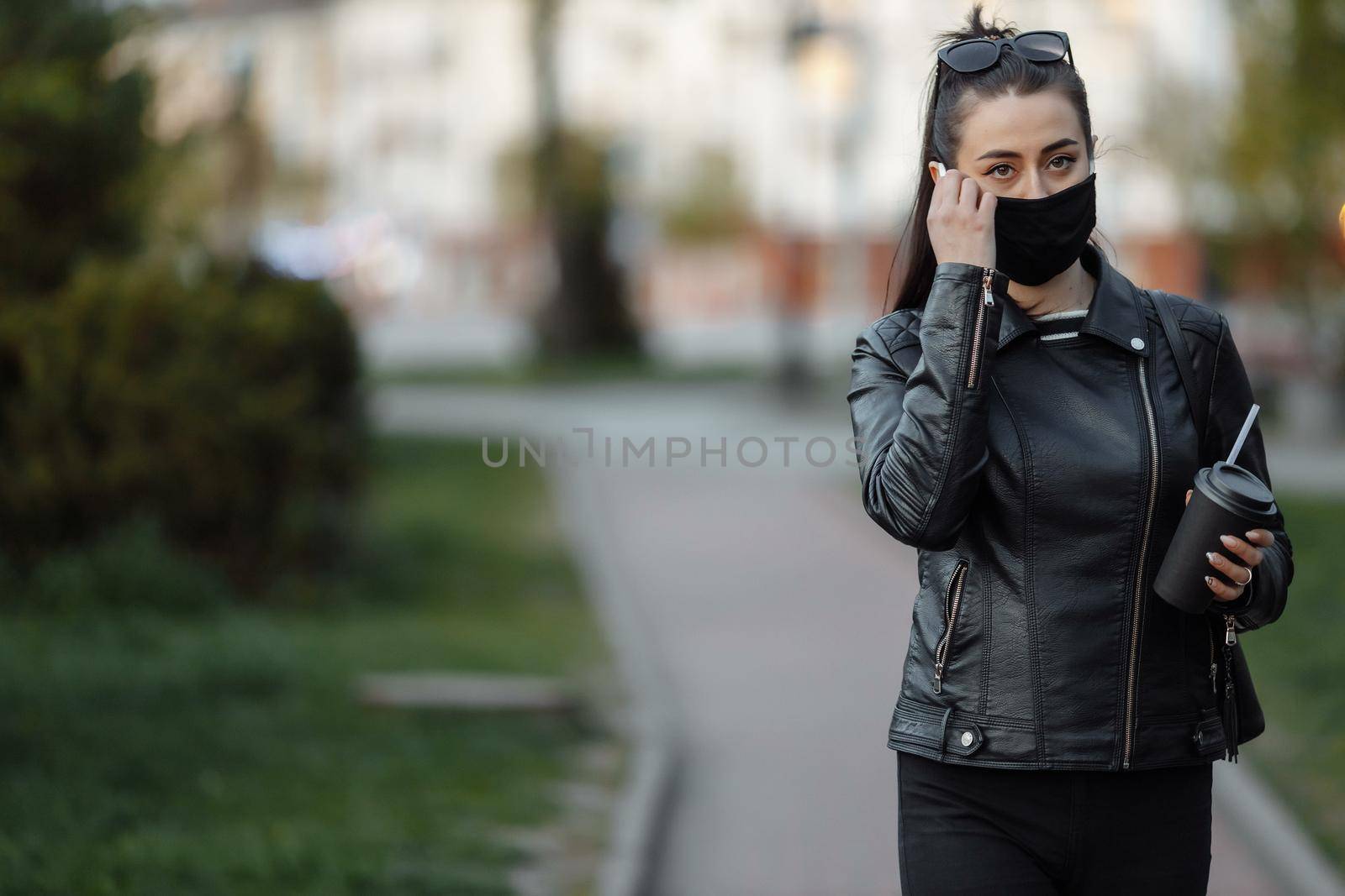 A masked girl is walking along the street. Coronavirus infection COVID-19.