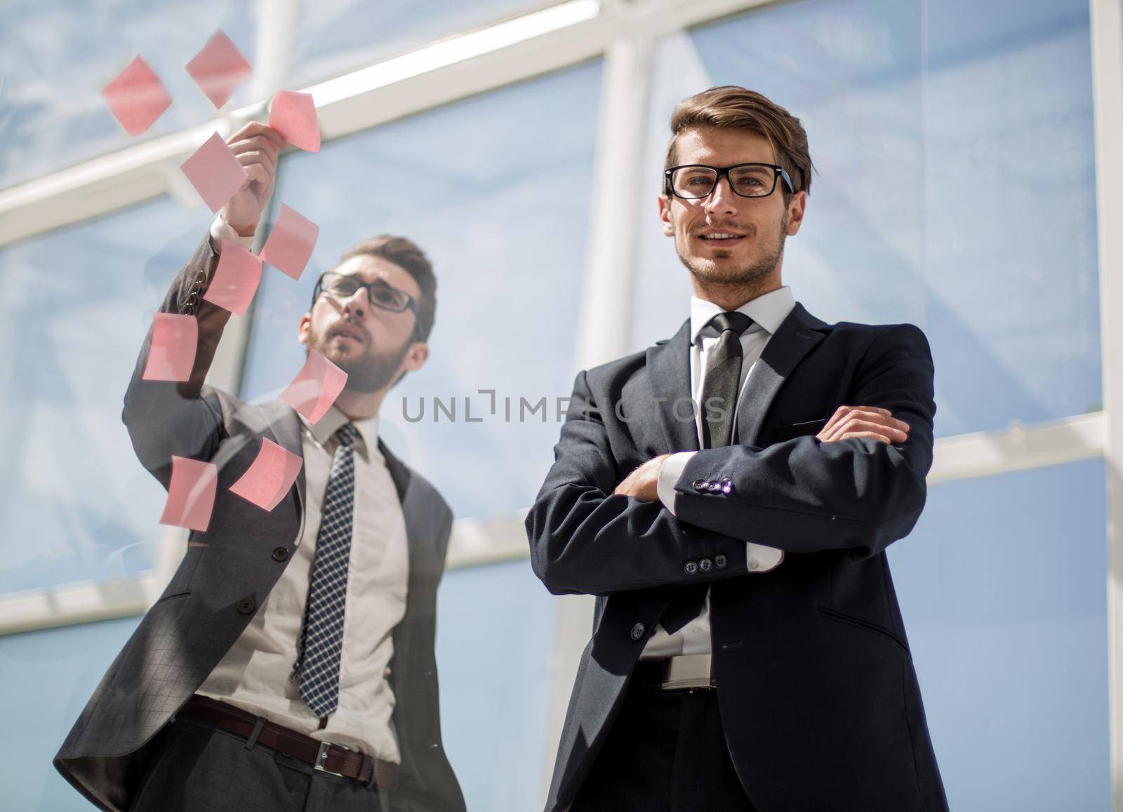 Business colleagues read stickers pasted on a transparent glass wall. by asdf