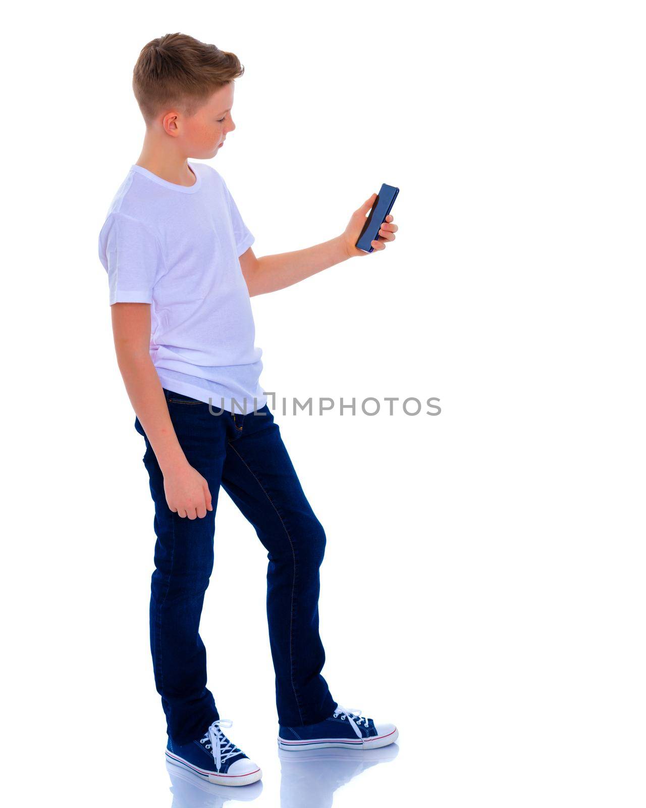 A small boy of school age uses a mobile phone. The concept of digital technology, communication between people. Isolated on white background.