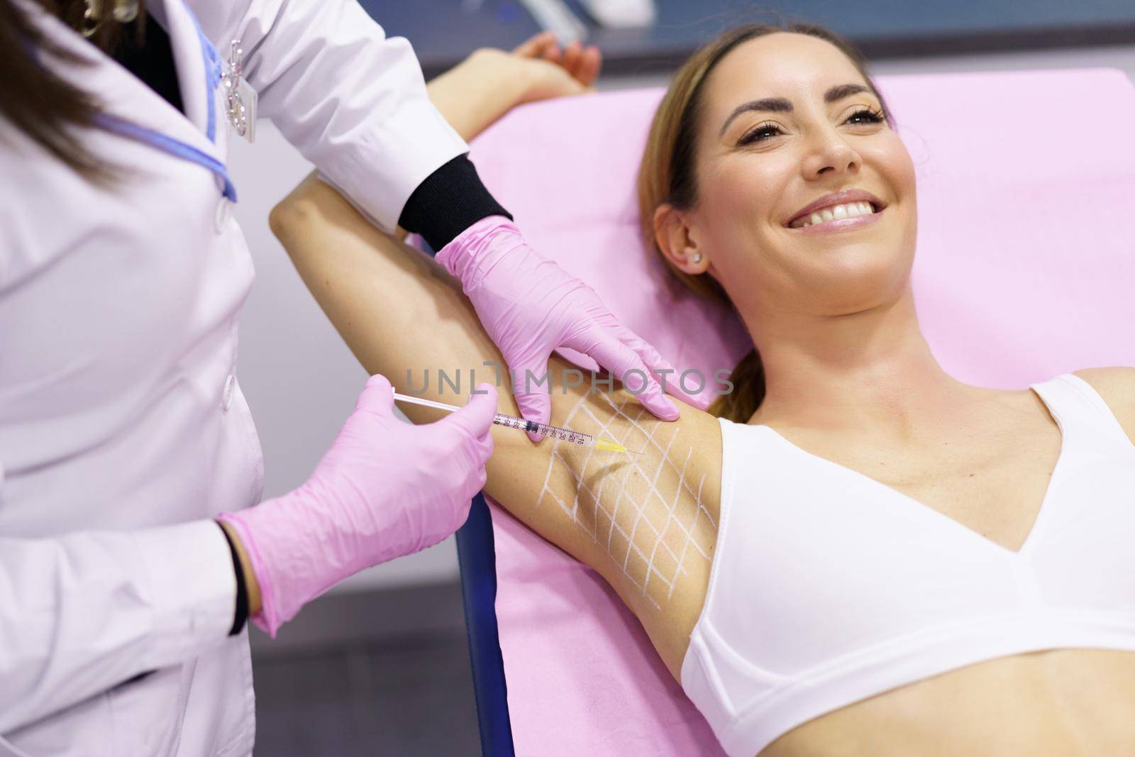 Doctor makes intramuscular injections of botulinum toxin in the underarm area against hyperhidrosis. by javiindy