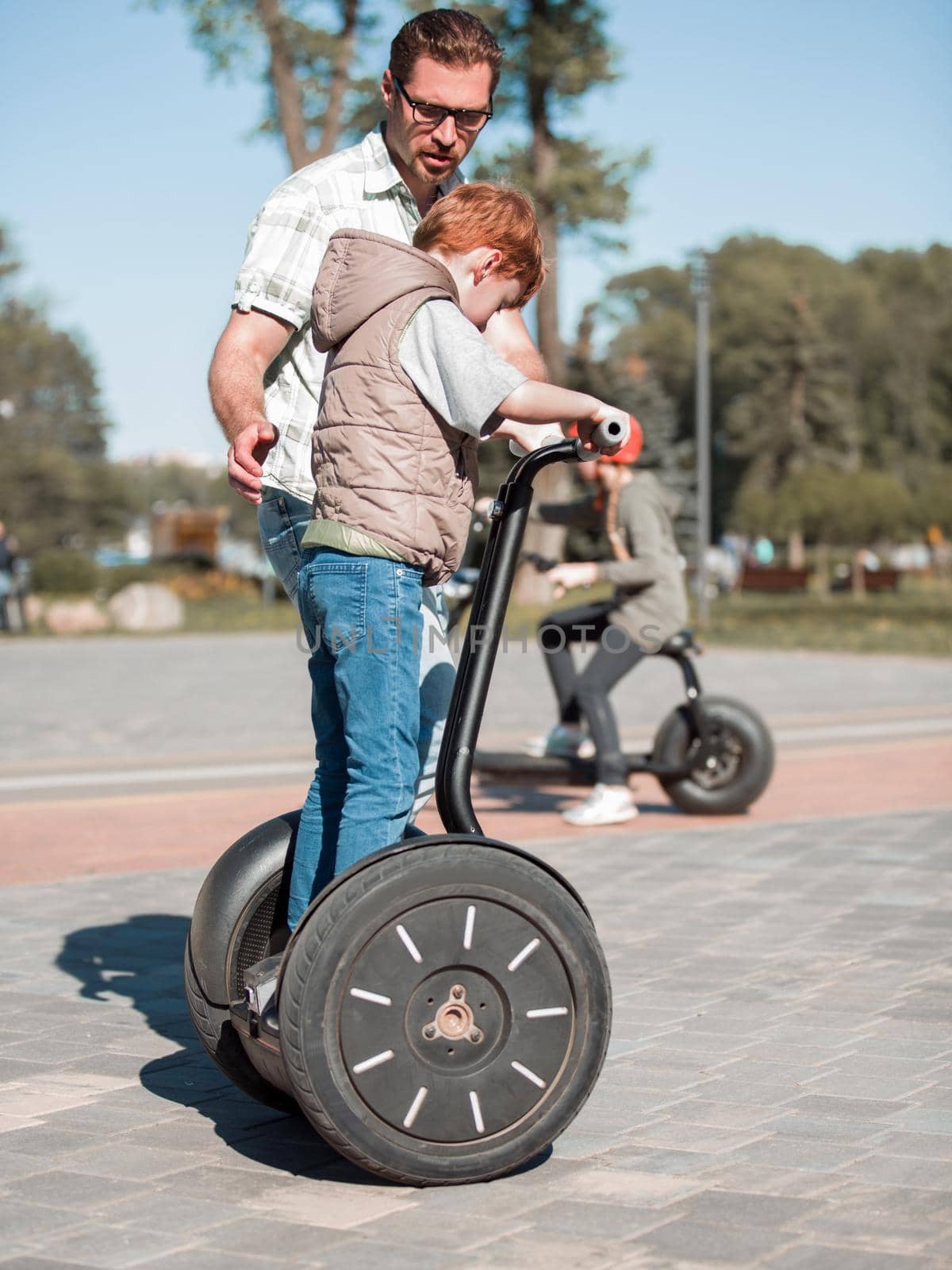 father teaches son to ride a mini-hoverboard in the Park. The family concept