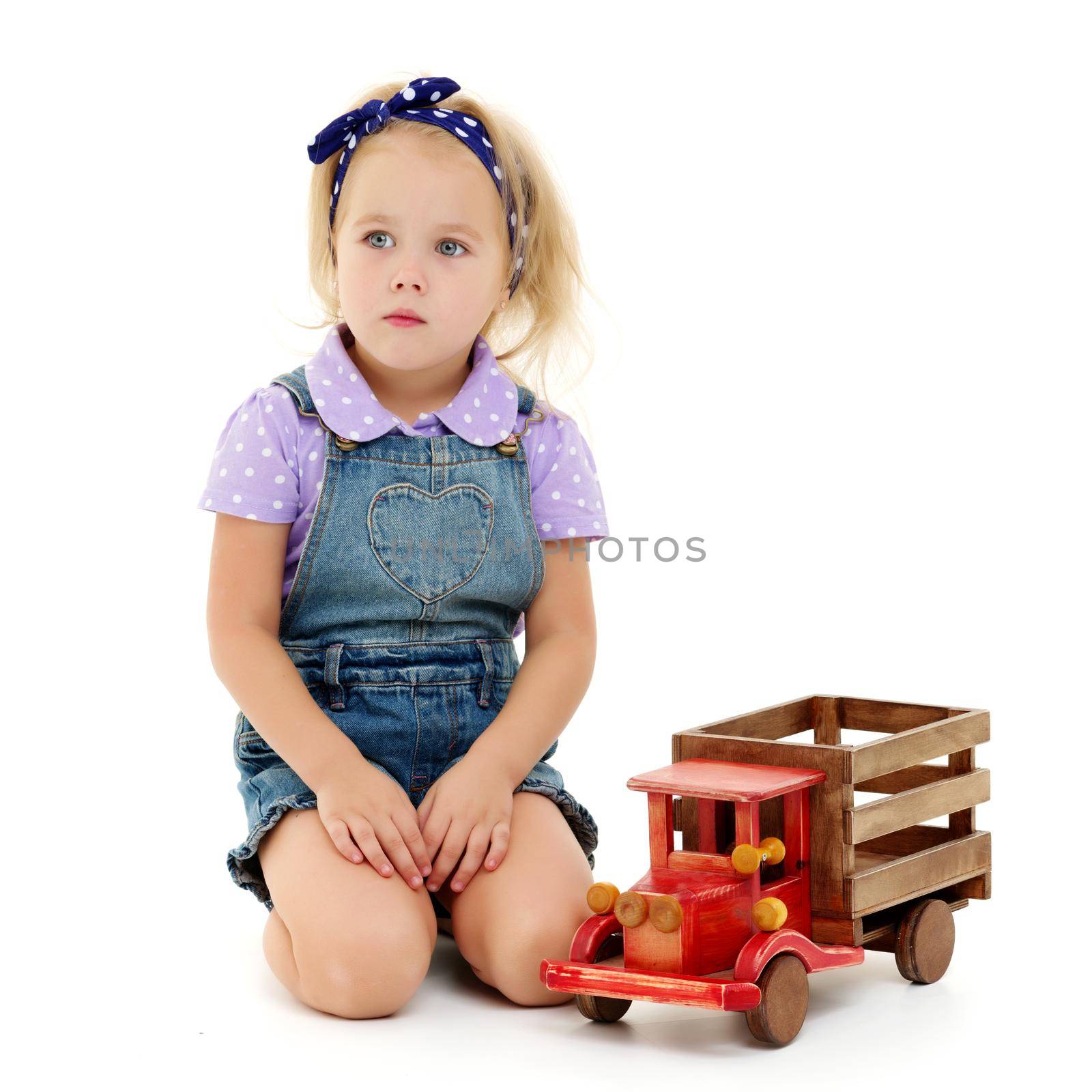 Little girl is playing with a wooden car. by kolesnikov_studio
