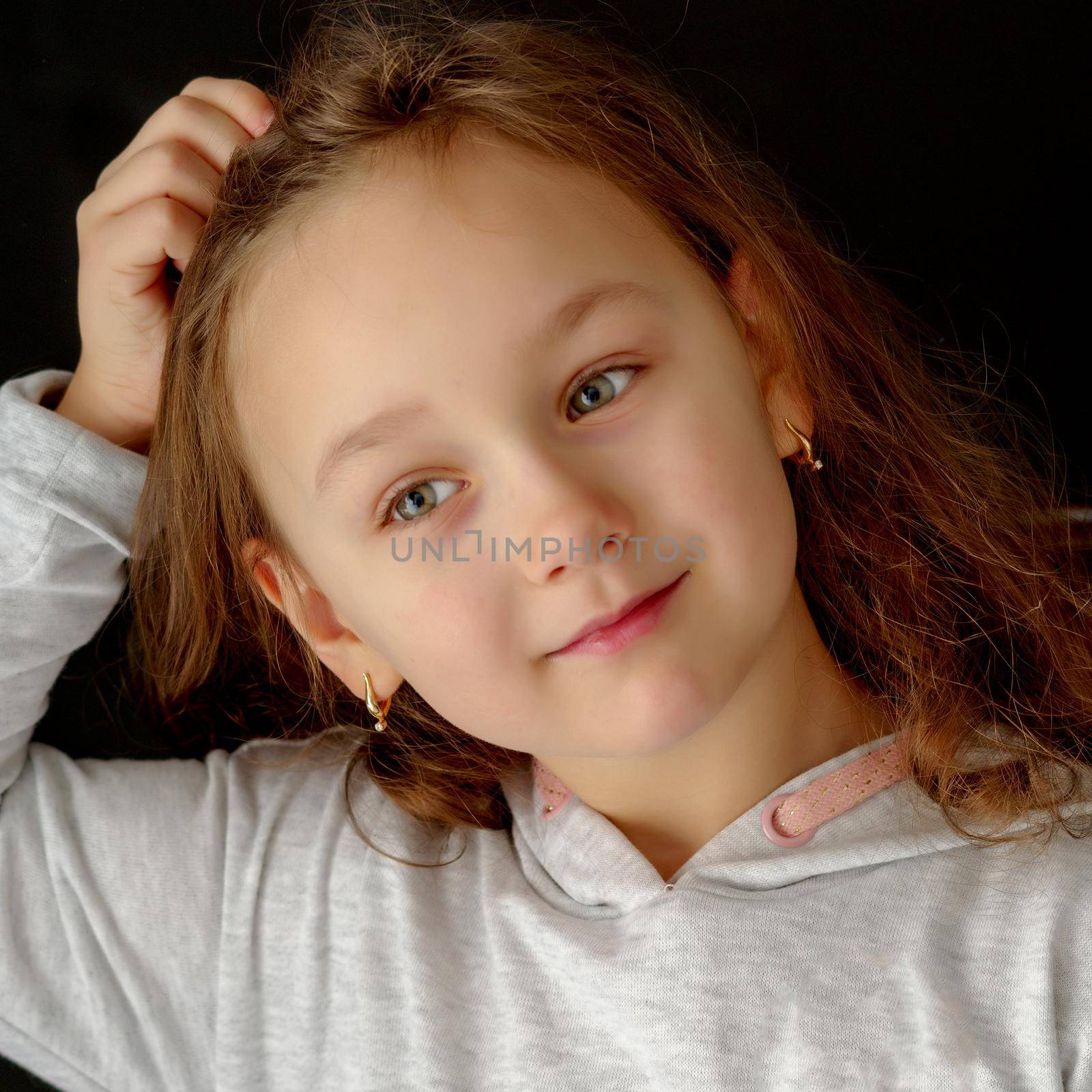 A beautiful little girl straightens her hair on her head. by kolesnikov_studio