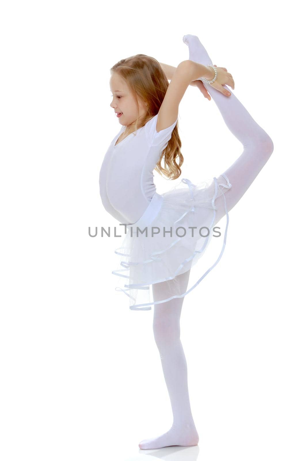 A girl gymnast balances on one leg.The concept of childhood, sport, a healthy lifestyle. Isolated on white background.