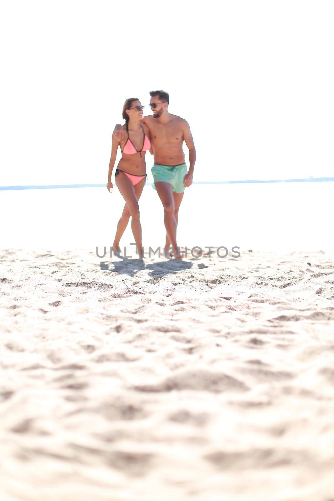 Young couple holding hands and walking on beach. by asdf
