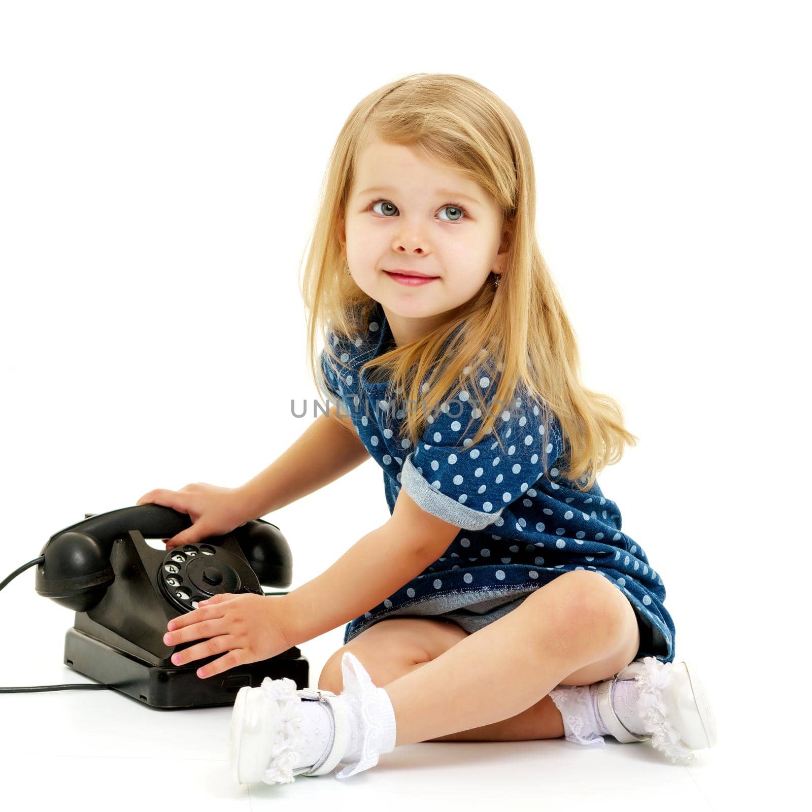 Cute little girl playing with an old phone. Concept retro, nostalgia. Isolated on white background.