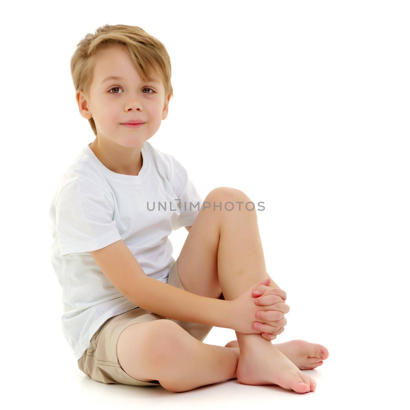 A sad little boy in a pure white T-shirt on the surface of which you can make a drawing or write advertising text. Isolated on white background.