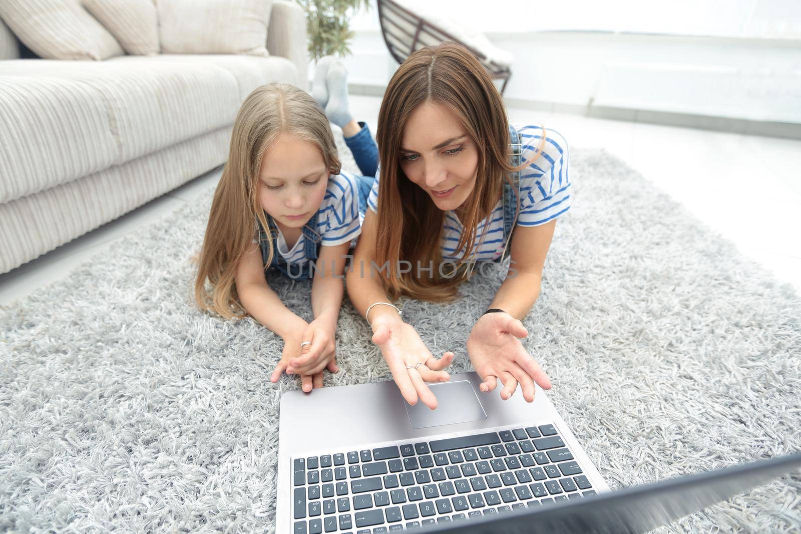 mom and daughter lying on the carpet and using a laptop.people and technology