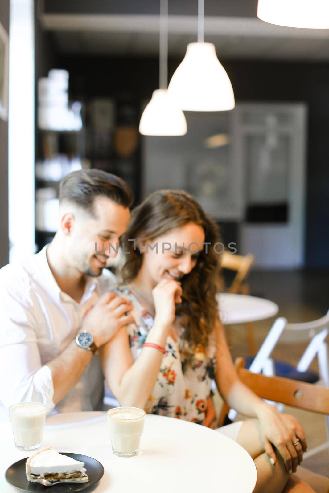 Young caucasian man hugging woman at cafe, ,sitting near cups of coffee. Concept of positive emotions, feelings and resting on lunch.