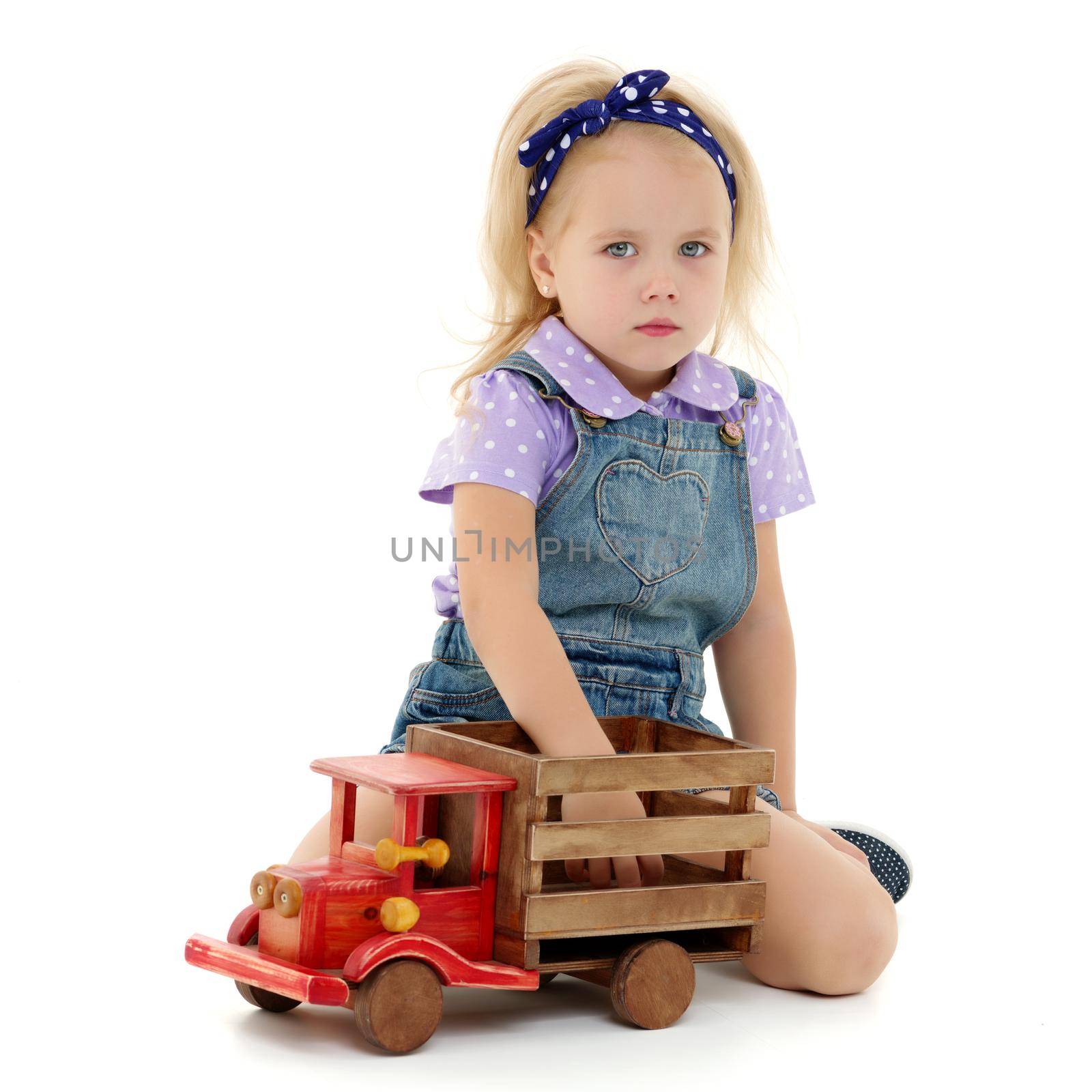 Little girl is playing with a wooden car. The concept of a happy childhood, playing in a kindergarten and family. Isolated on white background.