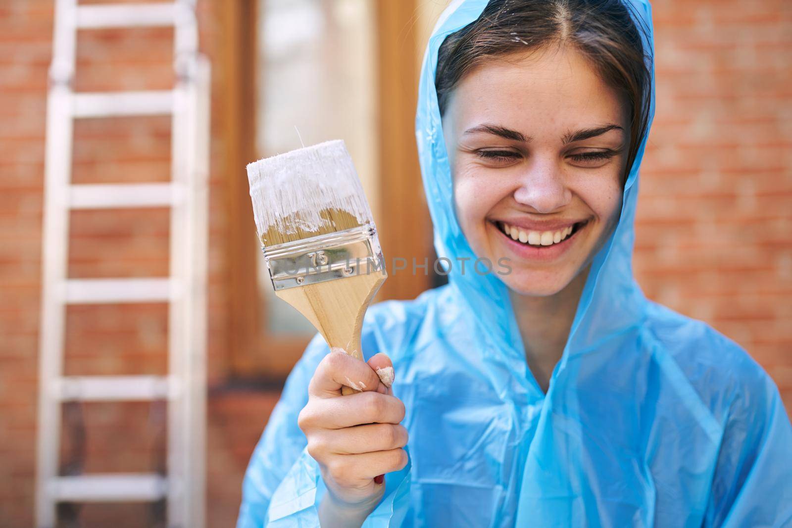 cheerful woman house painter in protective suit repairing home. High quality photo