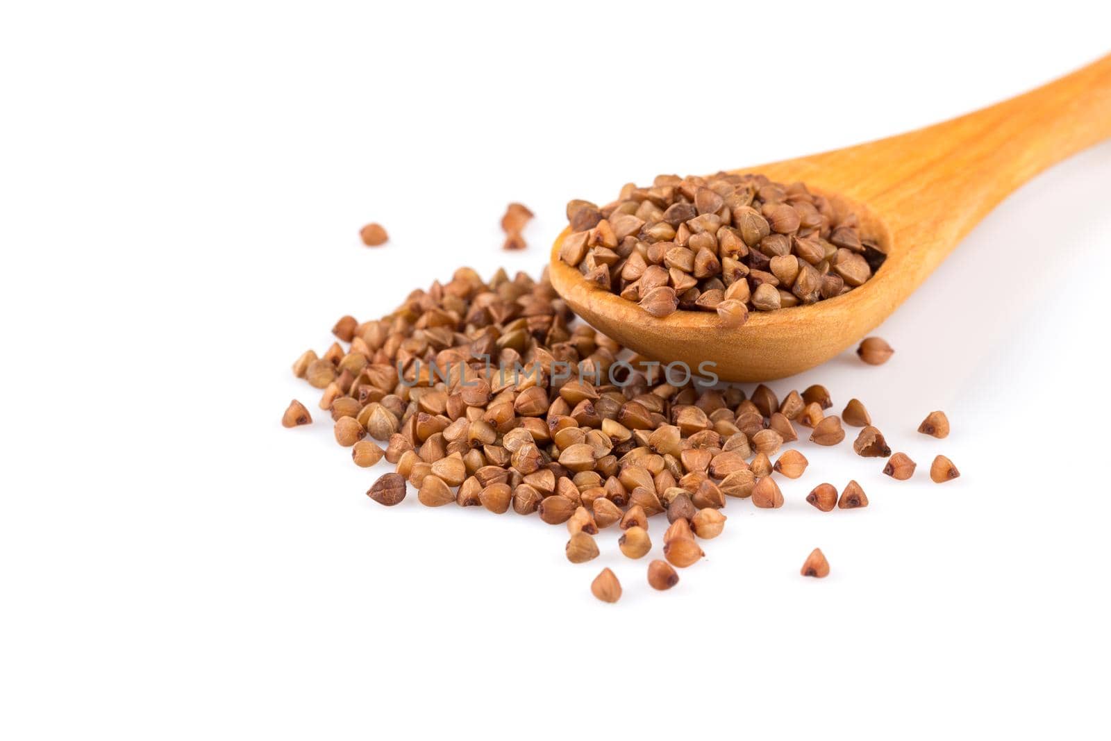 Uncooked buckwheat on wooden spoon. premium buckwheat groats on white background