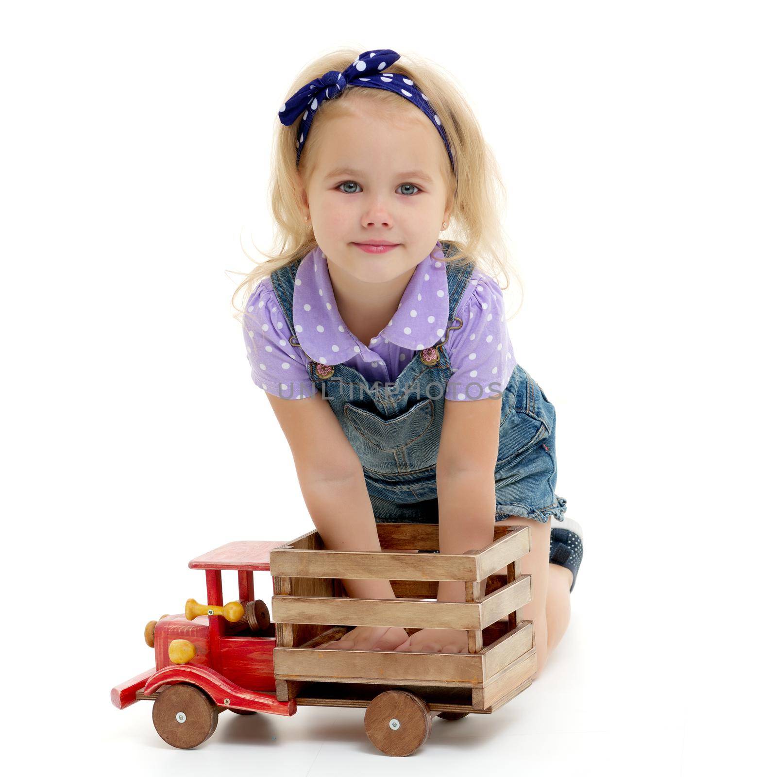 Little girl is playing with a wooden car. The concept of a happy childhood, playing in a kindergarten and family. Isolated on white background.