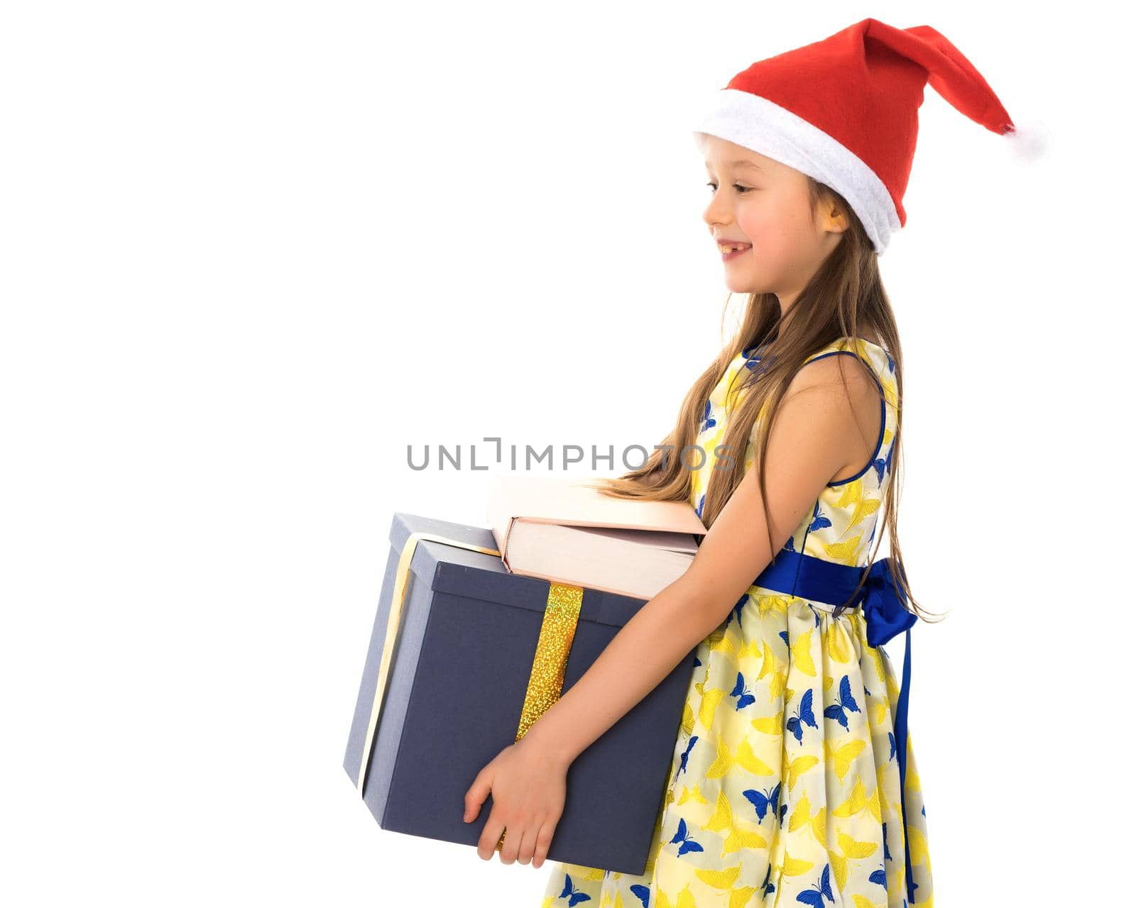 Beautiful little girl in a Santa Claus hat with a gift on a white background. The concept of Christmas, New Year's holidays. Isolated.