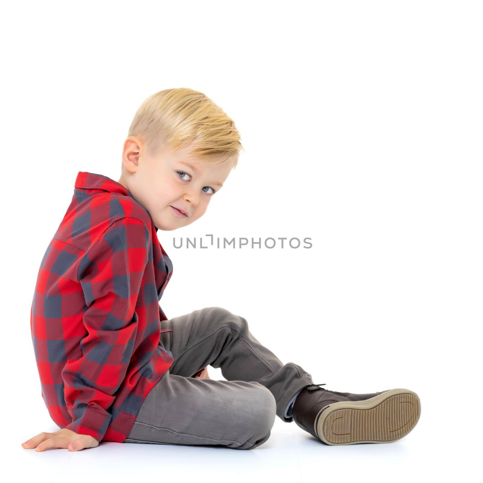 Cute little boy is sitting on the floor on a white background. The concept of a happy childhood, the harmonious development of the child in the family. Isolated.