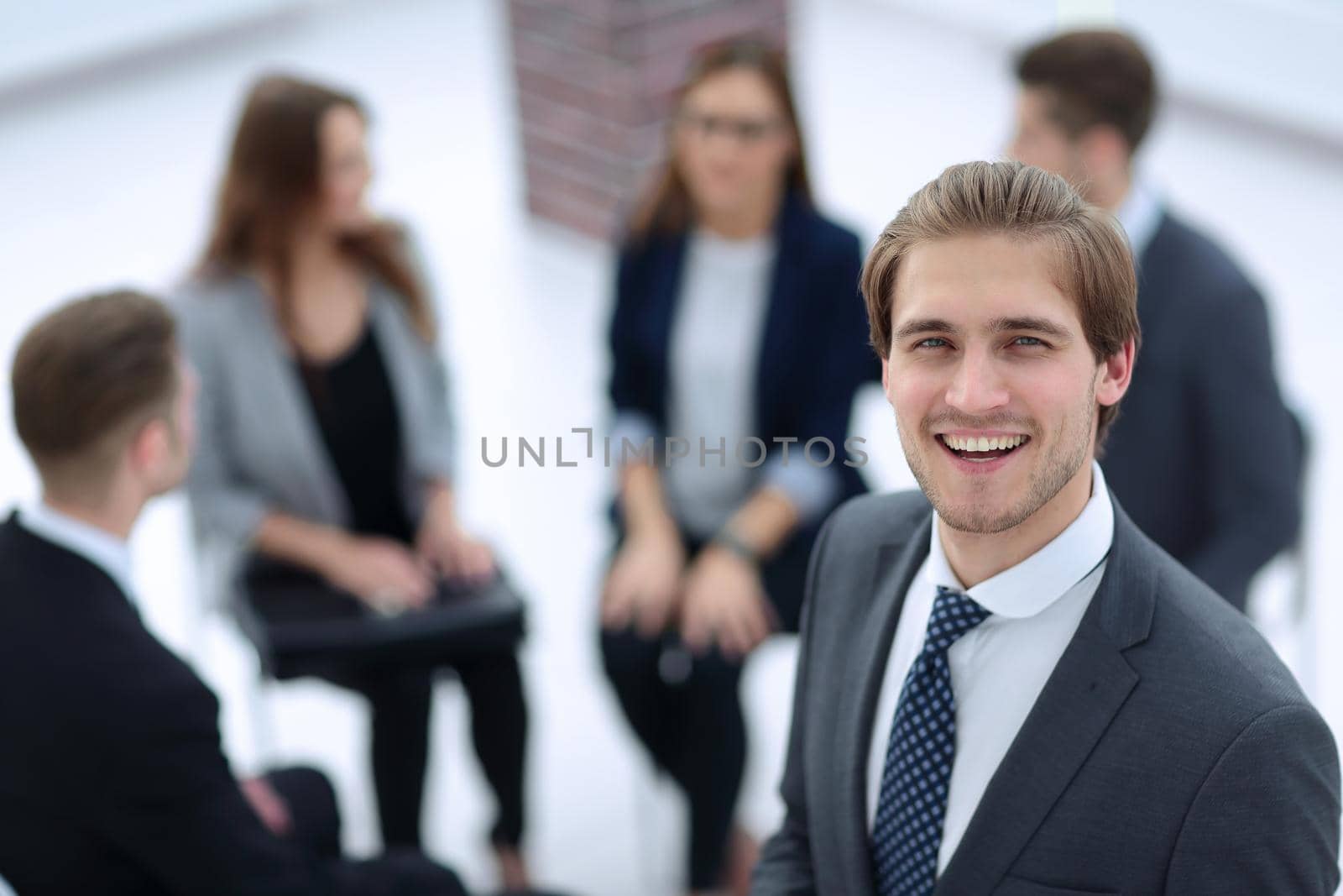 Happy businessman posing in front of his team while working on the background