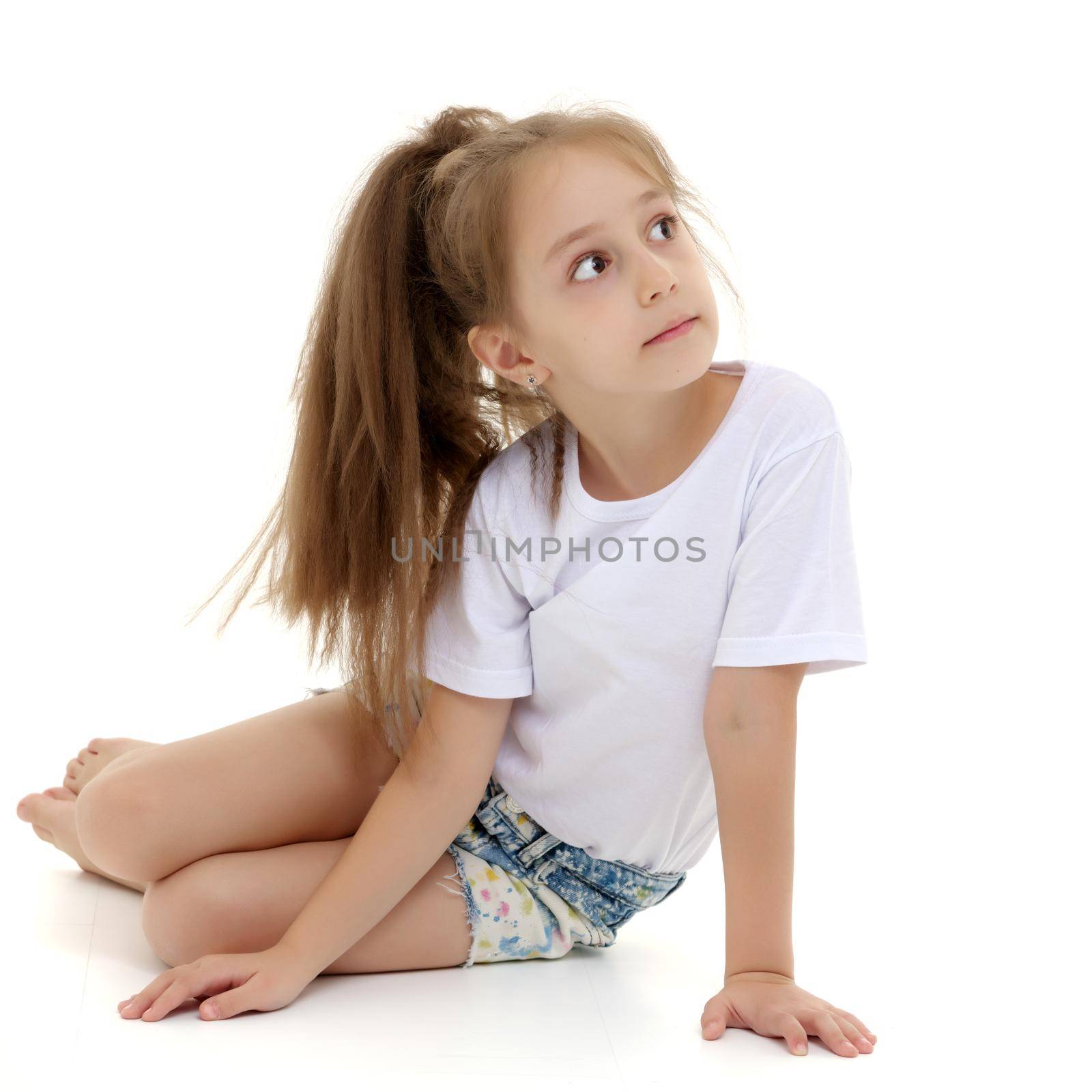 A charming little girl in short shorts and a pure white T-shirt on which you can make any inscription. The concept of advertising, including children's products. Close-up. Isolated on white background.