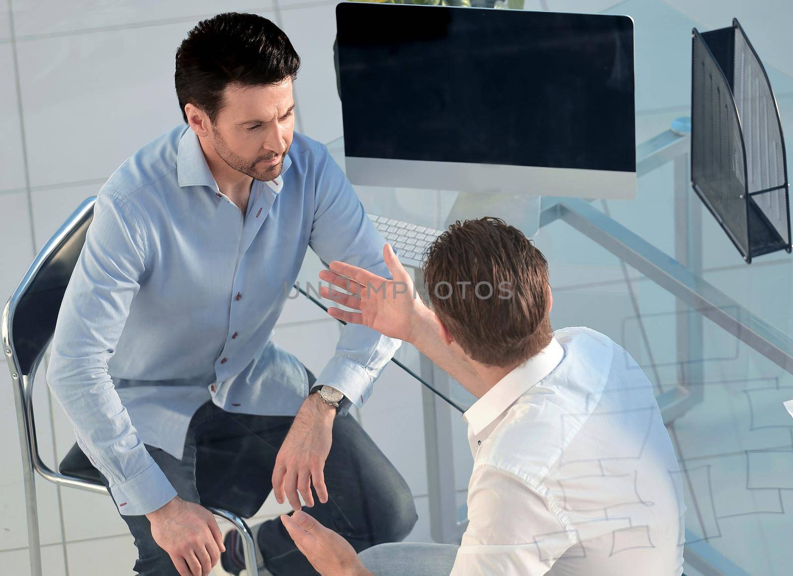 top view.the Manager and the client are talking, sitting at the office table