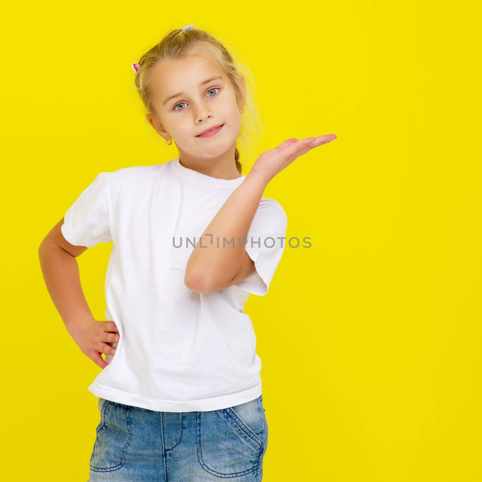 Emotional little girl in a clean white T-shirt. The concept can be used to advertise goods and services, whose logo can be printed on the surface of the shirt.On a yellow background.