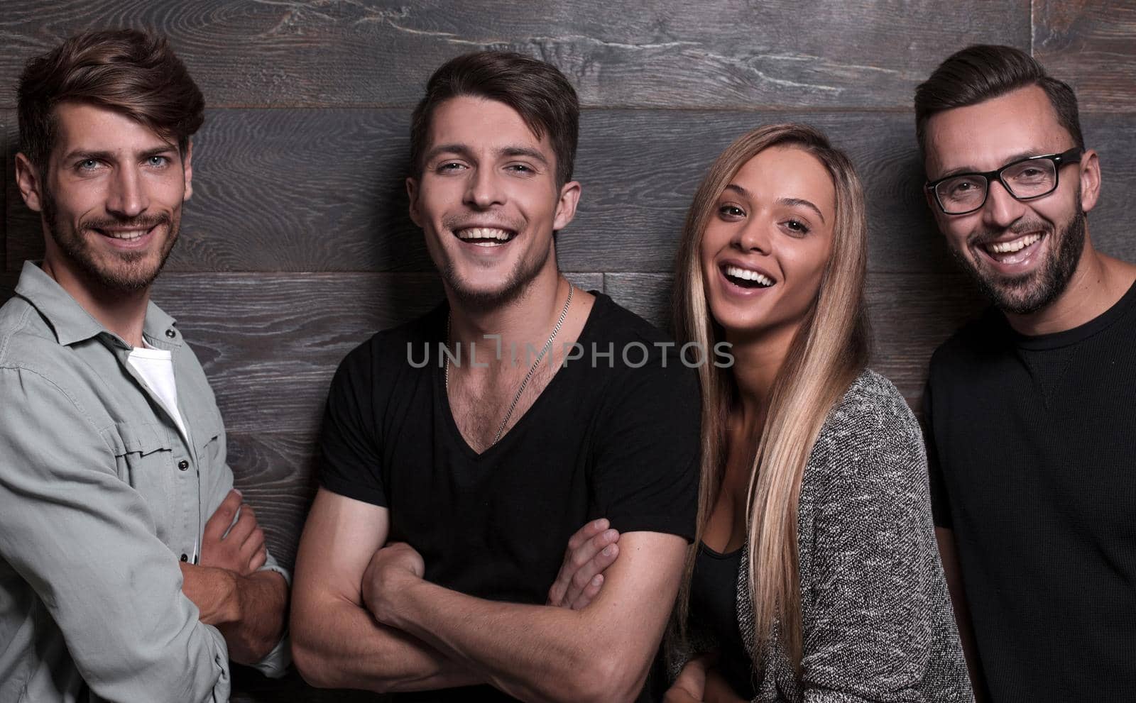 Attractive group of young people posing grouped close together looking at the camera with warm friendly smiles