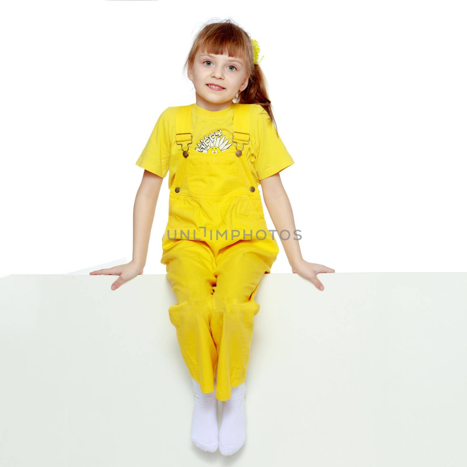 Girl with a short bangs on her head and bright yellow overalls. by kolesnikov_studio