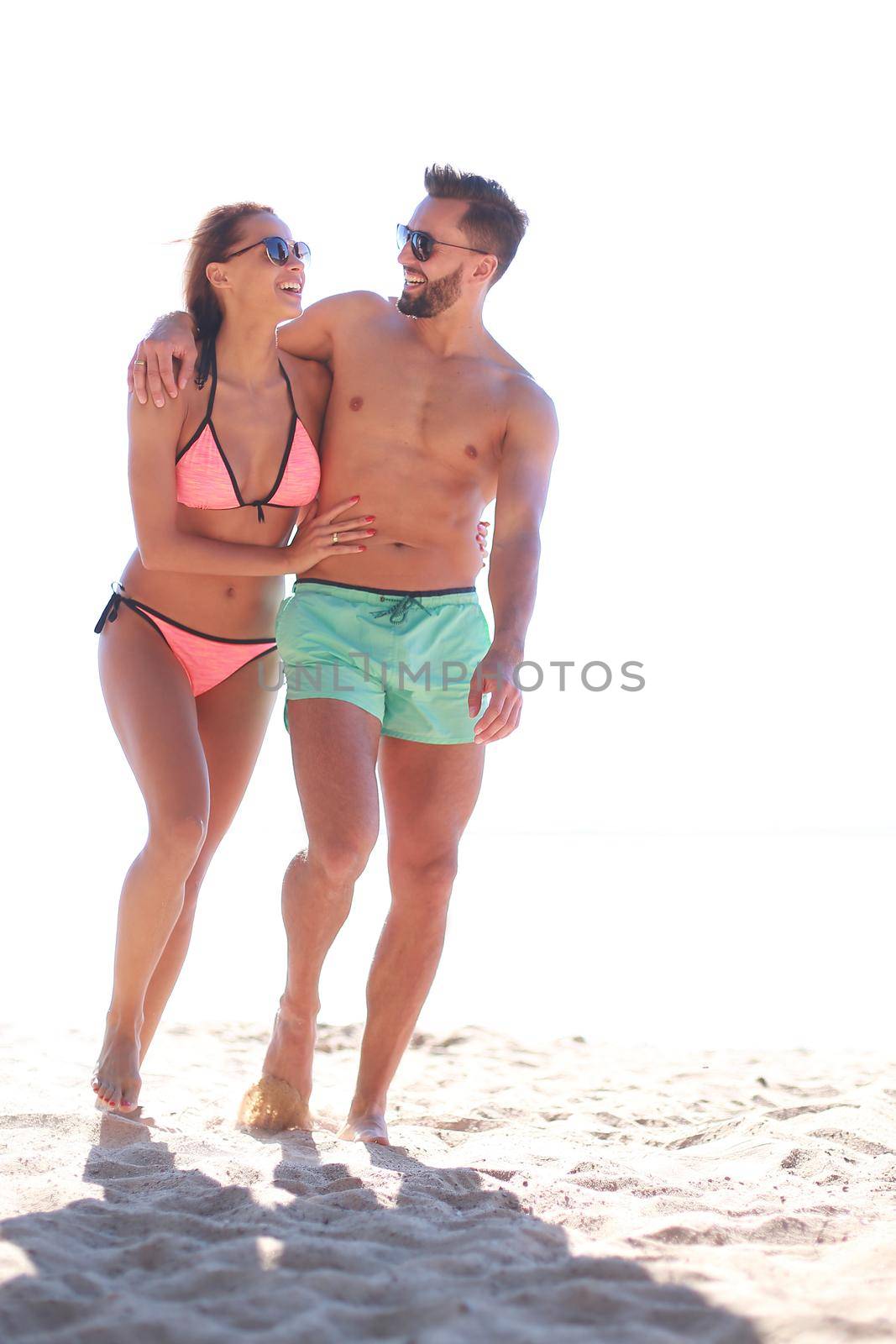 Young couple holding hands and walking on beach. by asdf