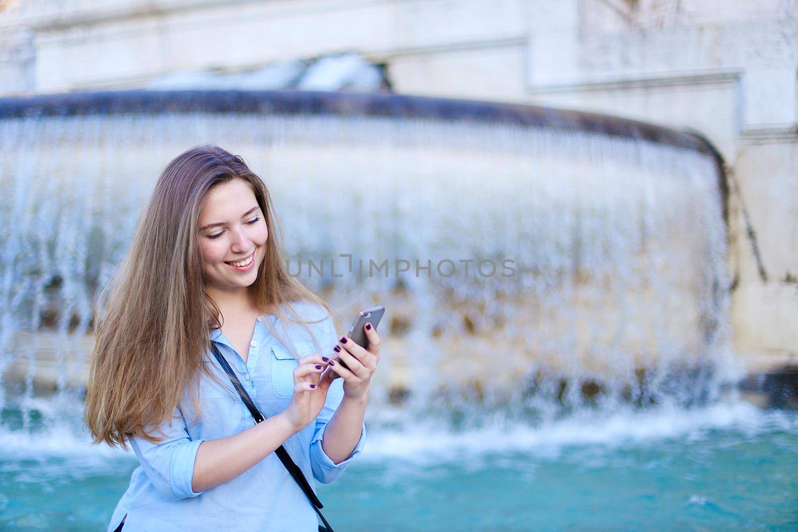 Young caucasian girl chatting by smartphone in Trevi fountain background. by sisterspro