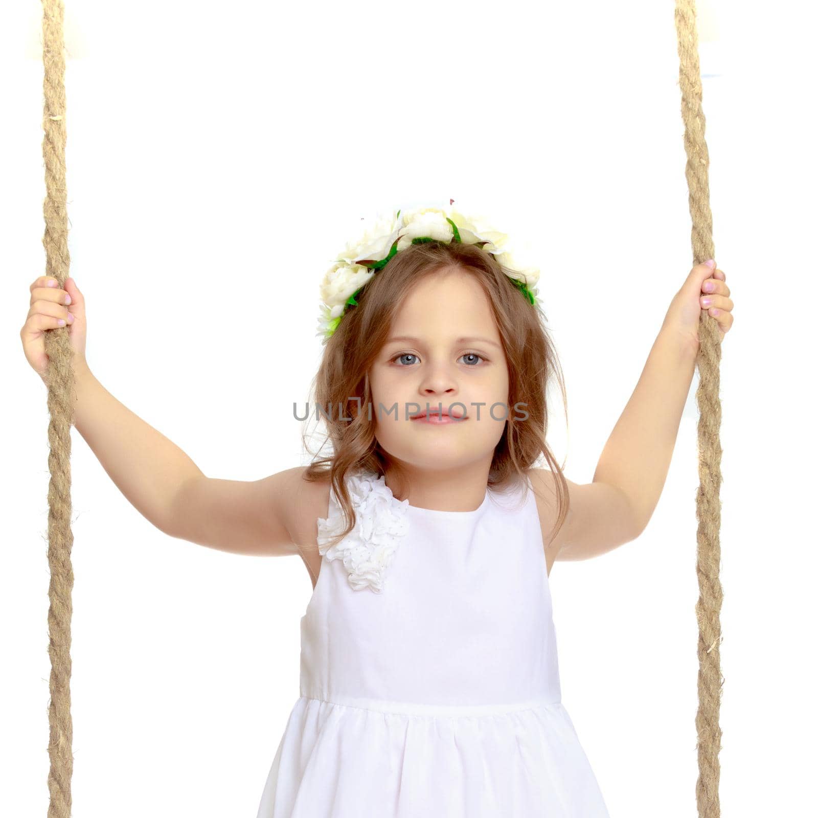 Adorable little girl swinging on a swing. She is happy to have fun and show how she can do it. The concept of summer recreation and harmonious development of the child. Isolated on white