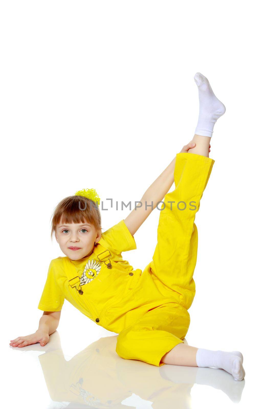 Girl with a short bangs on her head and bright yellow overalls.She crouched down on the white advertising banner.