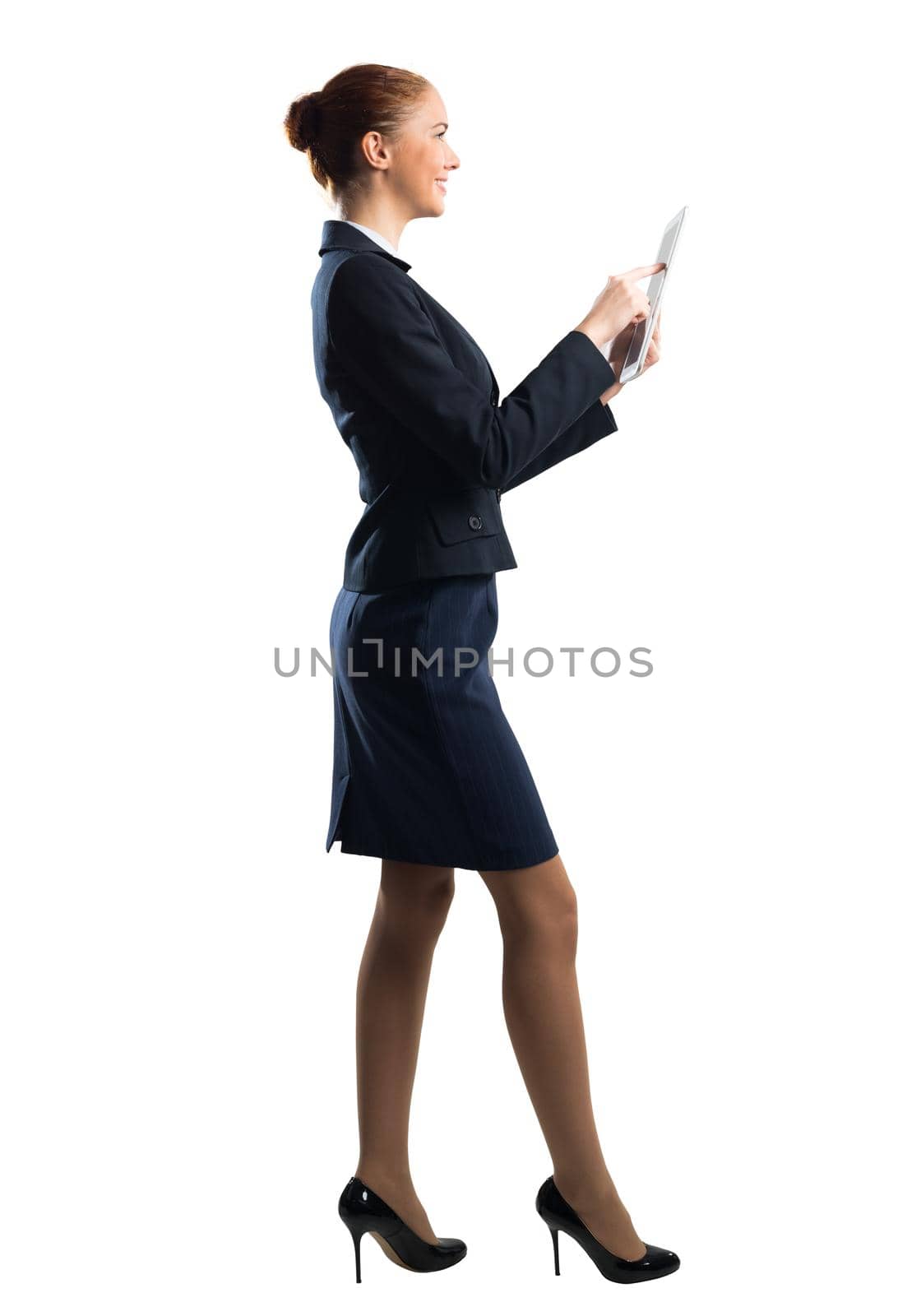 Portrait of young woman looking at screen of tablet computer. Side view of confident businesswoman in dark blue suit. Corporate businessperson isolated on white background. Online communication layout